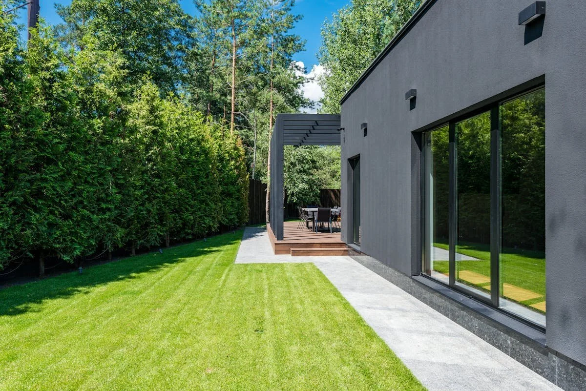 Modern house with green lawn and patio surrounded by trees under sunny sky. GLO advises on Zoning and Development issues. Contact Geraghty Law Office: Real Estate & Business Law. Trusted Legal Support in Denver, Colorado.