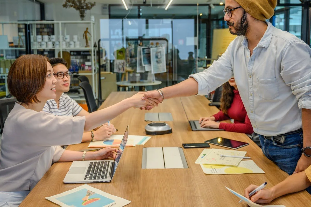 Two people shaking hands at a table during meeting. GLO prepares and reviews Asset Purchase Agreements and assists with Business Purchases and Sales. Contact Geraghty Law Office: Real Estate & Business Law. Trusted Legal Support in Denver, Colorado.