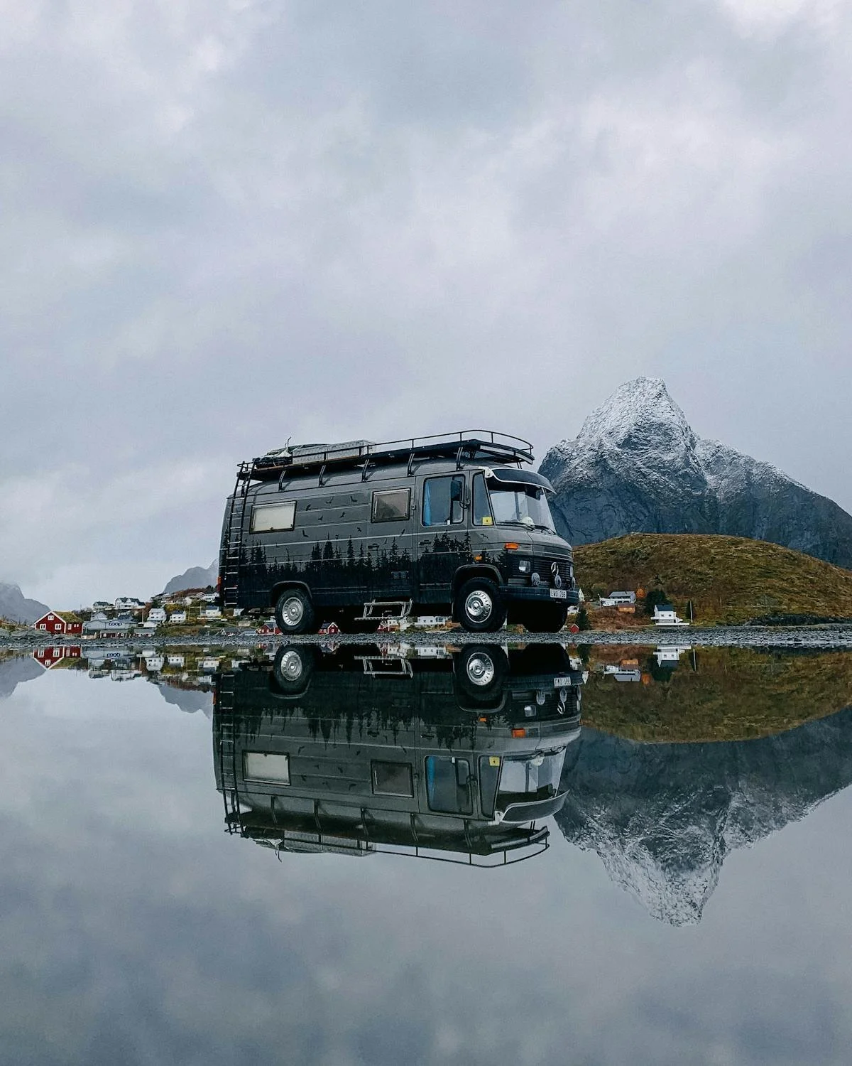 Black camper van reflecting in water below with mountains behind. GLO assists with Mobile Home Park Transactions in Colorado. Contact Geraghty Law Office: Real Estate & Business Law. Trusted Legal Support in Denver, Colorado.