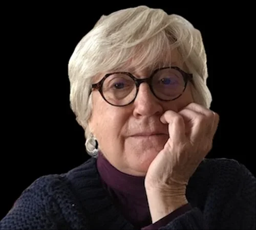 Woman wearing glasses with chin resting in her palm on a black background.
