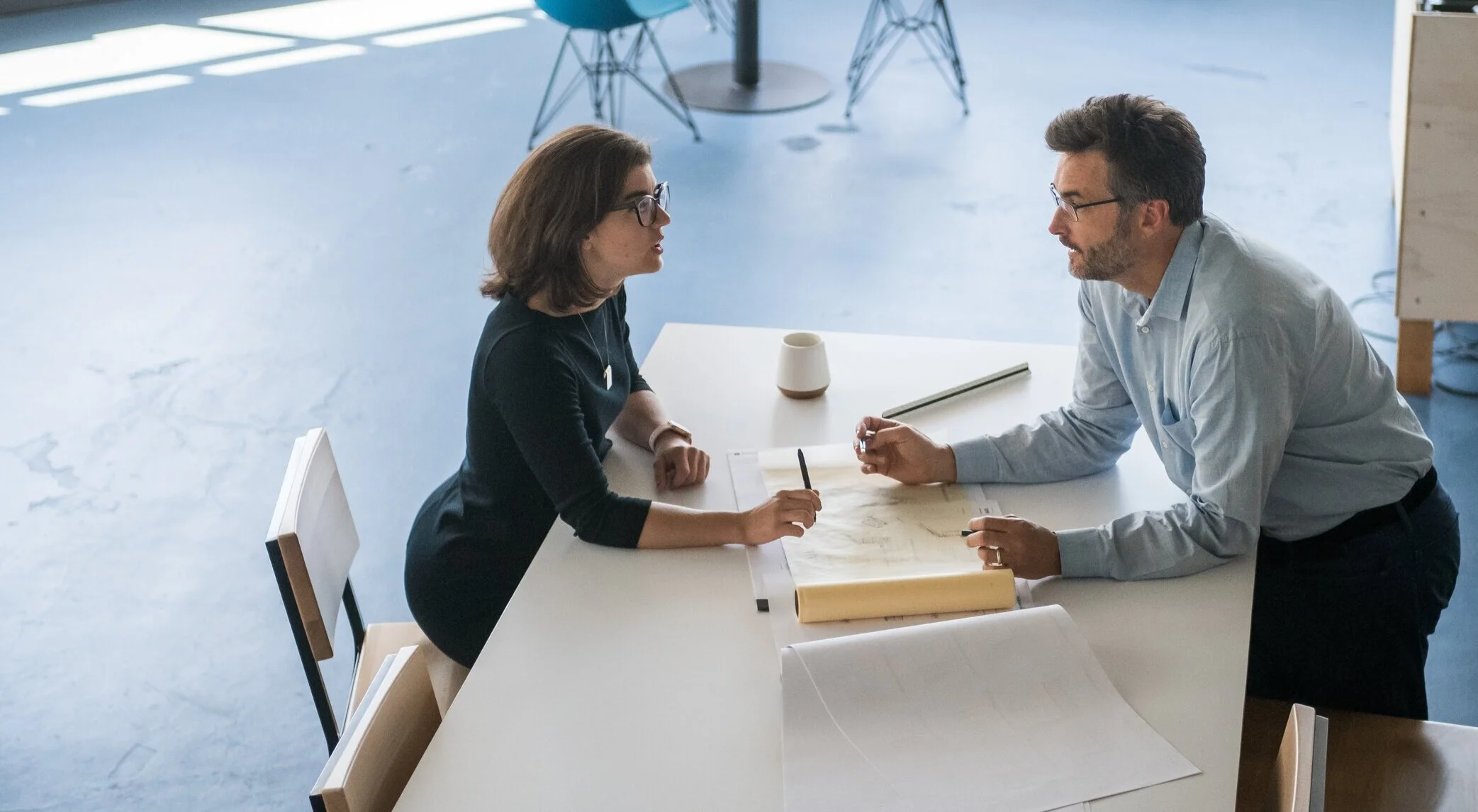 Photo of a man and a woman discussing business over a white table in an office setting