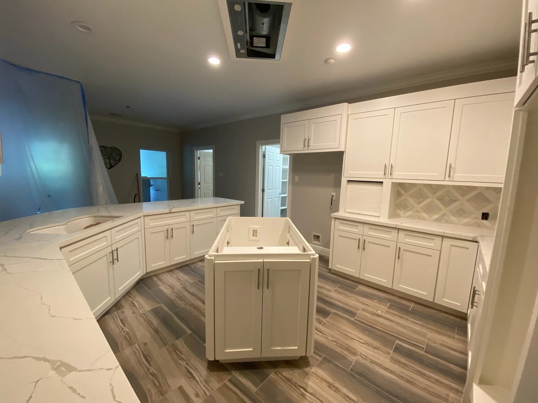 Kitchen renovation with updated wood cabinetry, painted cabinets & new hardware, marbled quartz countertops, white & gray stone tile backsplash throughout. Updated flooring.
