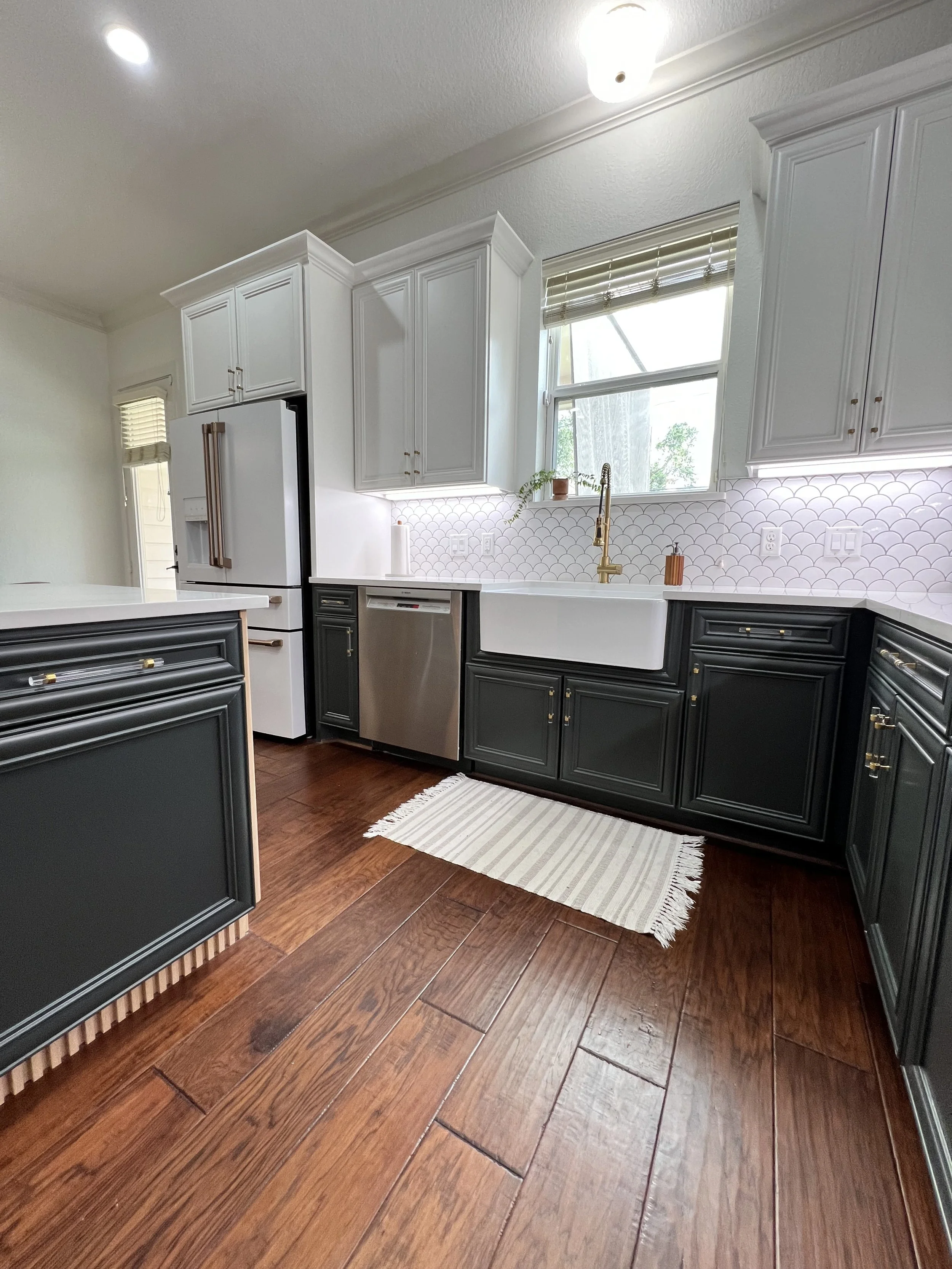 Kitchen remodel including cabinet painting & hardware installation, install of new sink & hardware, new lighting install, ceramic backsplash & fluted oak paneling on kitchen island.