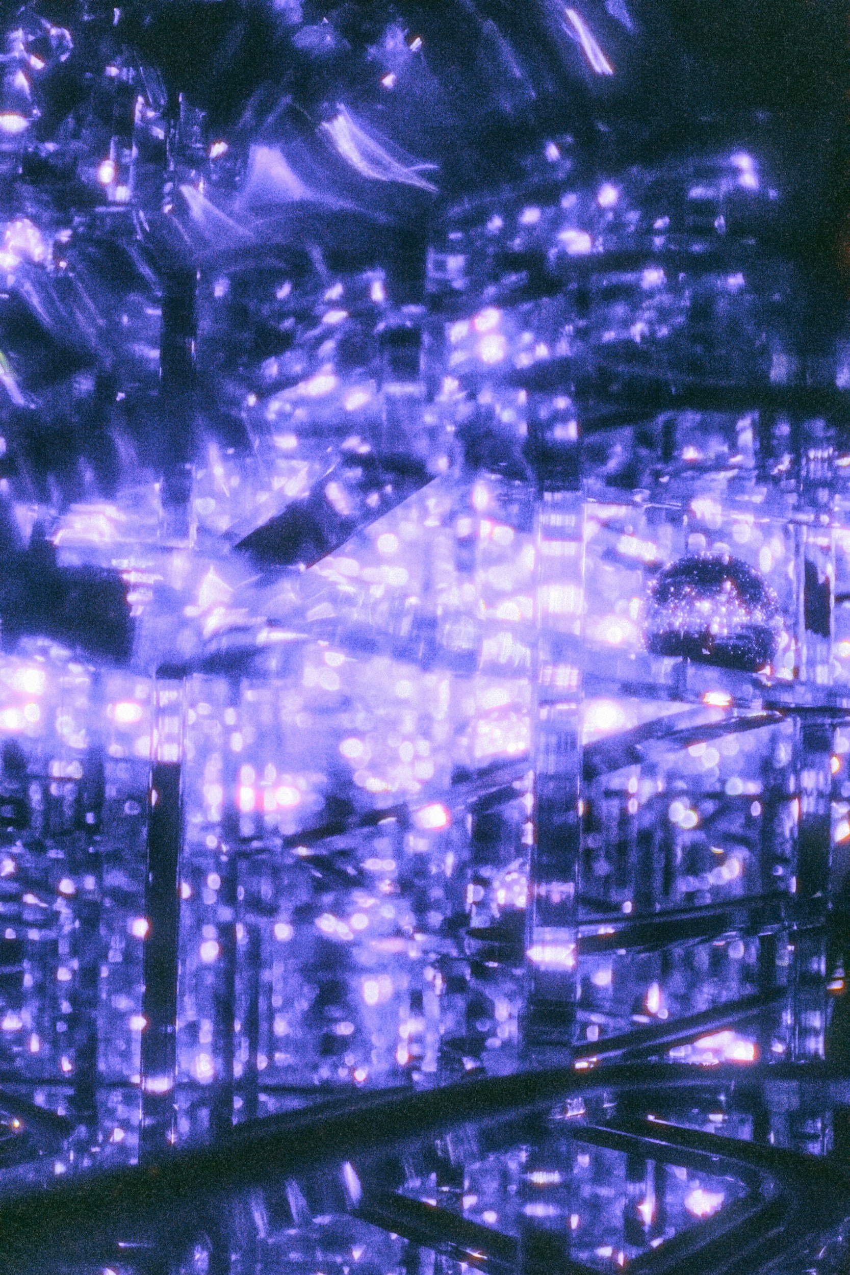 A futuristic, abstract scene with glowing purple and blue lights reflecting off transparent surfaces, creating a complex, luminous pattern.