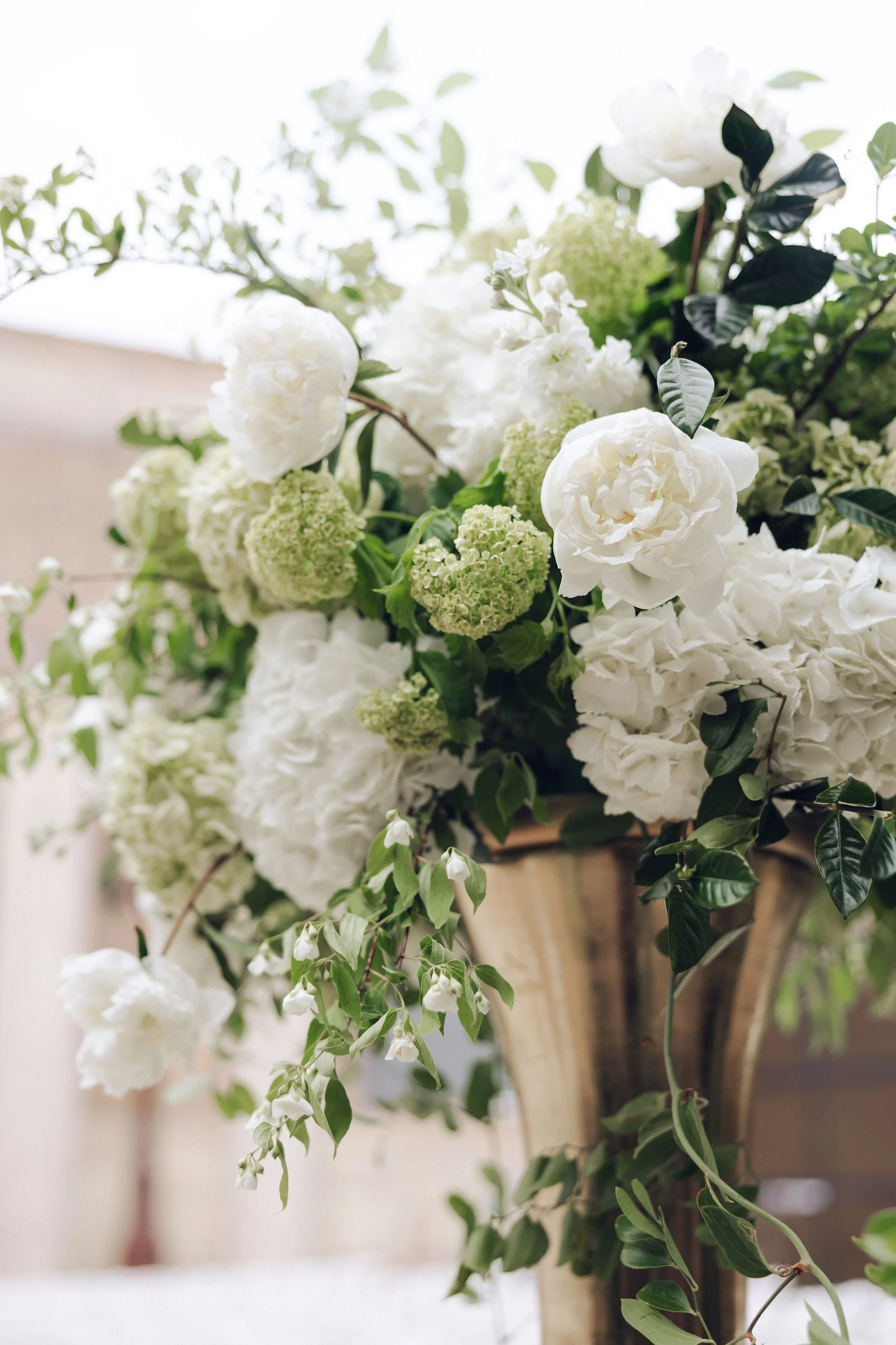 A floral arrangement with white and green flowers in a golden vase