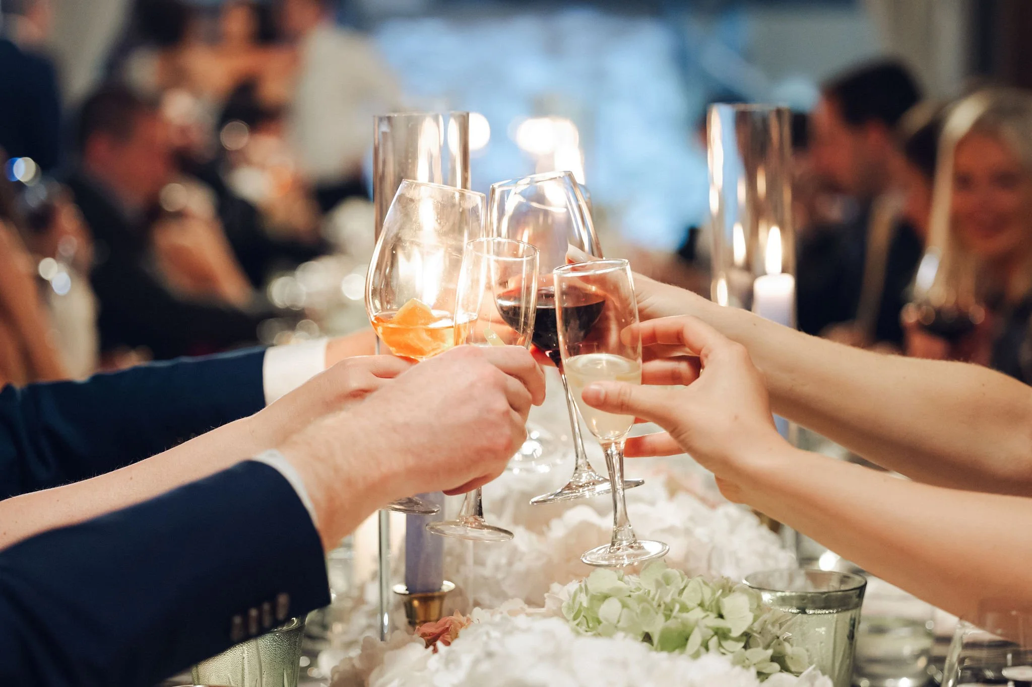 People toasting with glasses of wine at a formal dinner party.