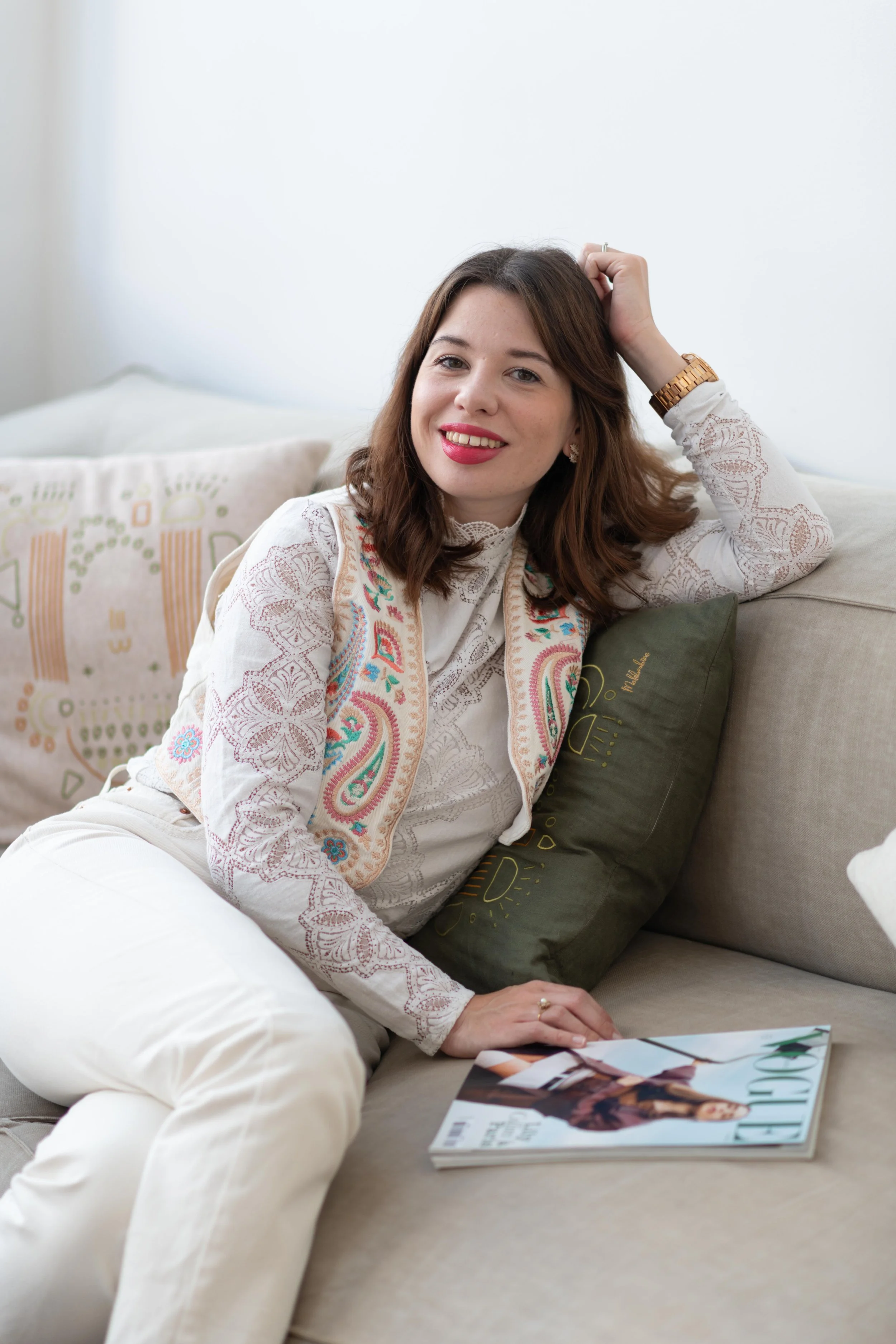 Femme assise sur un canapé, tenant un magazine, sourire, décoration intérieure