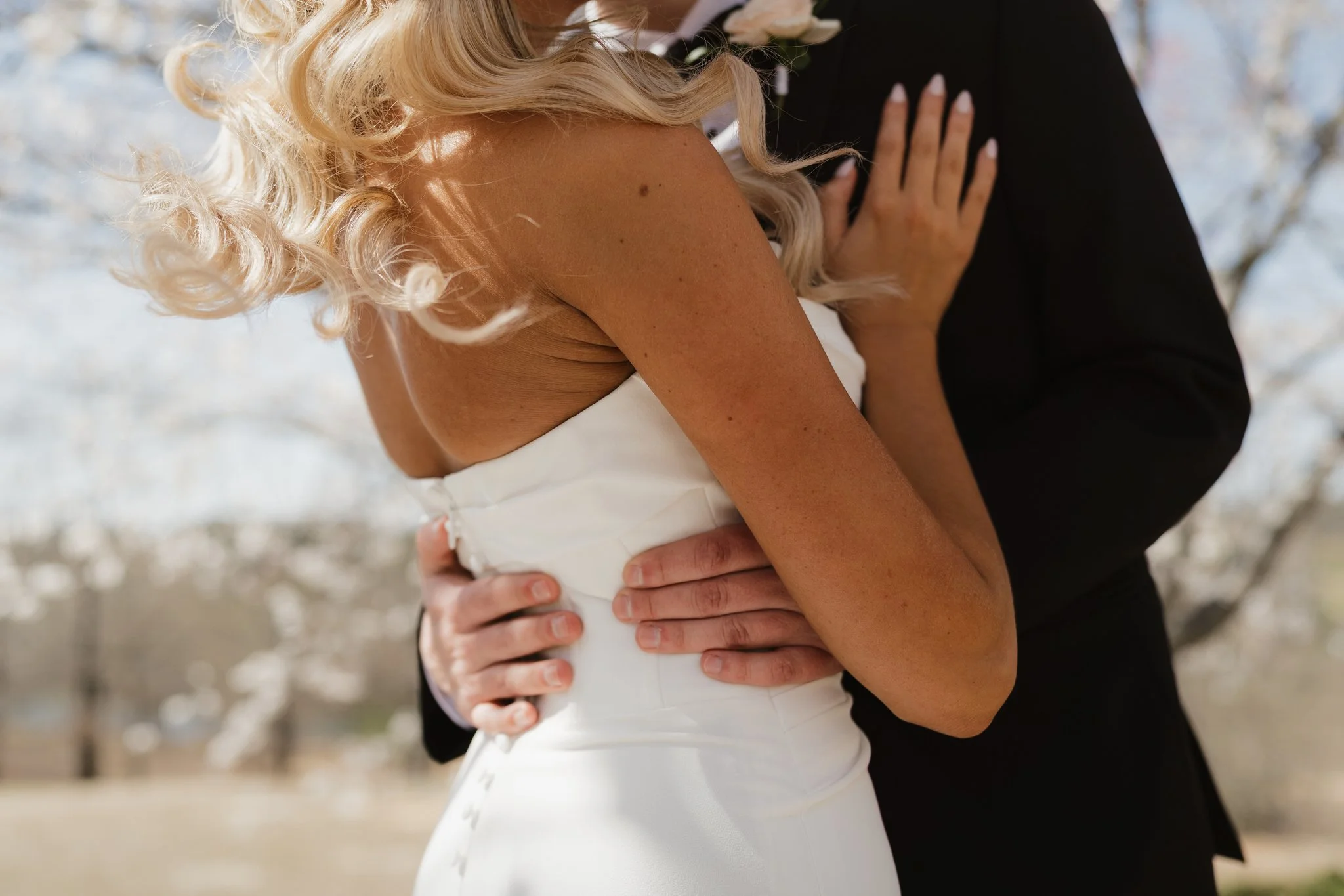Close-up of a bride and groom embracing outdoors, with the bride wearing a white dress and the groom in a black suit, during a winter wedding in Memphis, TN. 