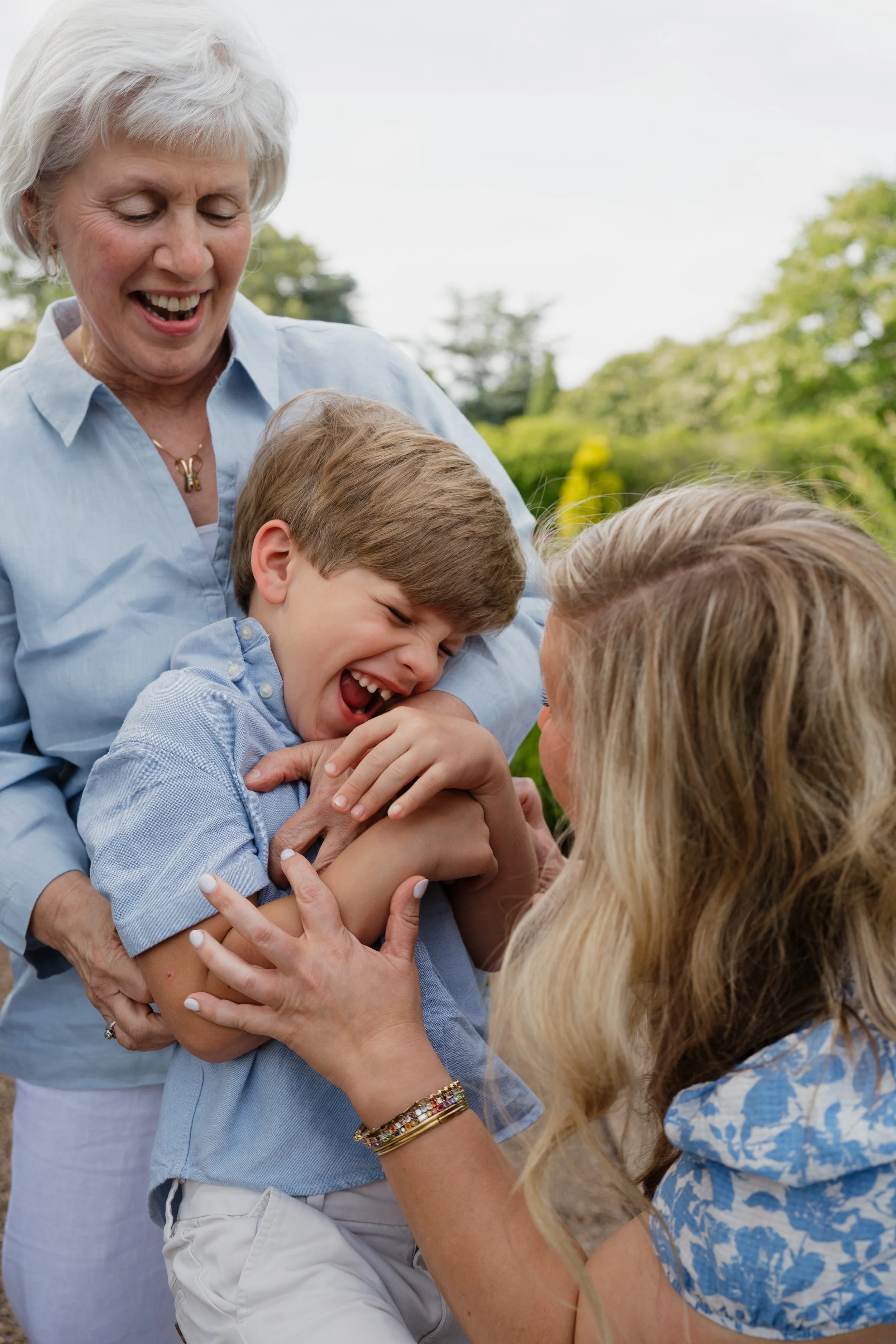 A grandmother, daughter, and grandson all laughing embrace one another during a family photo shoot in Memphis, TN.