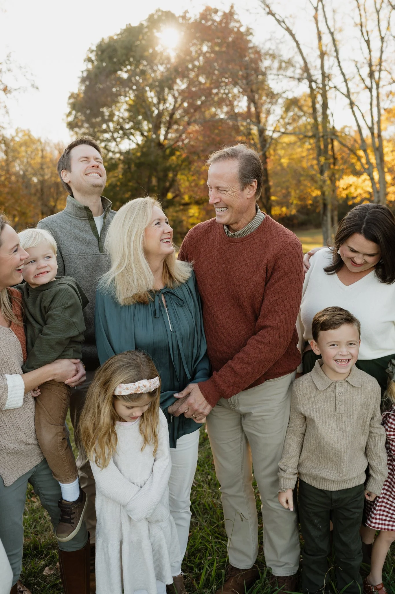 A group of smiling people, including children and adults, standing outdoors in a park with autumn-colored trees, enjoying a sunny day in Memphis, TN. 
