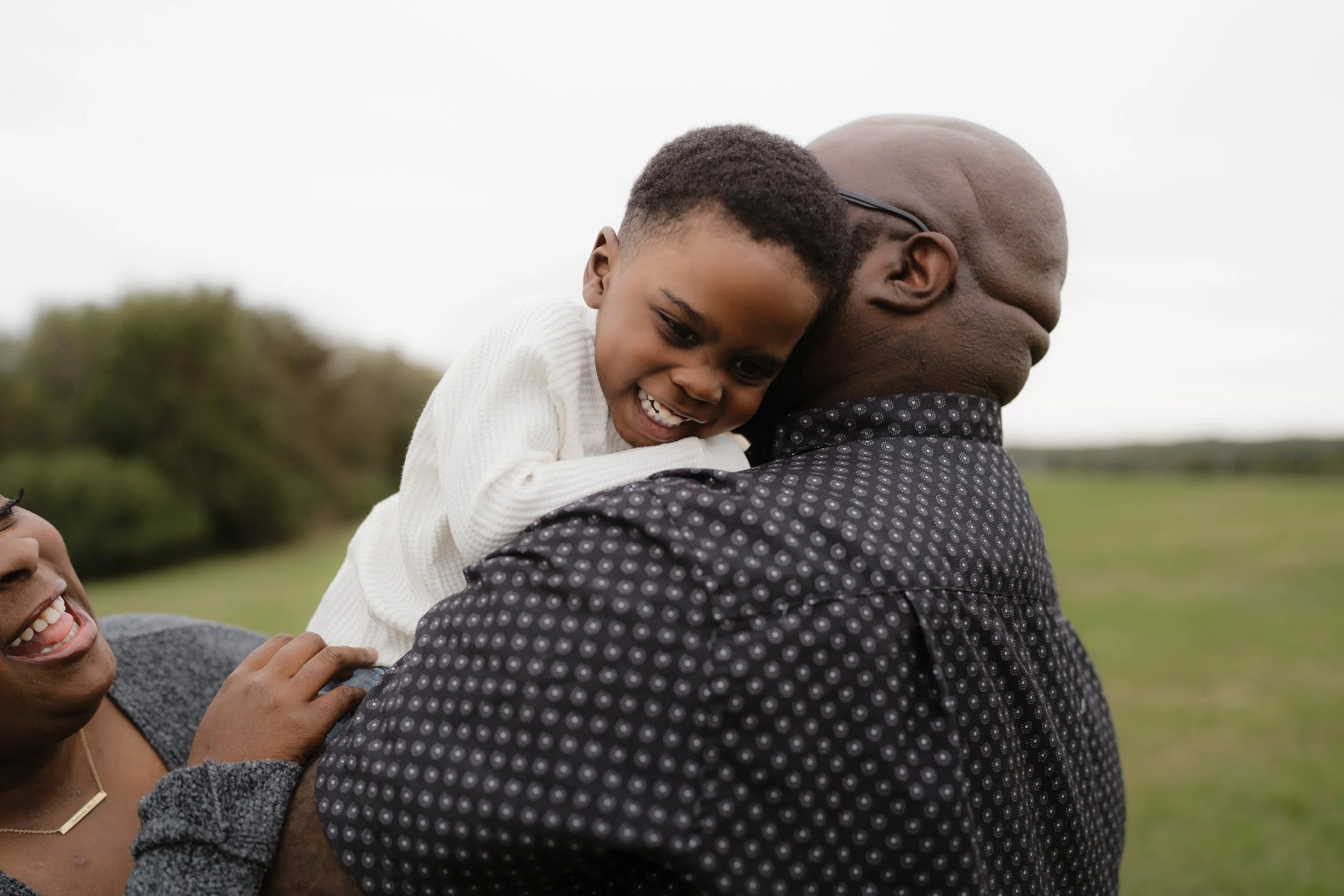 A young girl with short hair hugging a man at an outdoor event, with a woman smiling nearby in the background in Memphis, TN. 