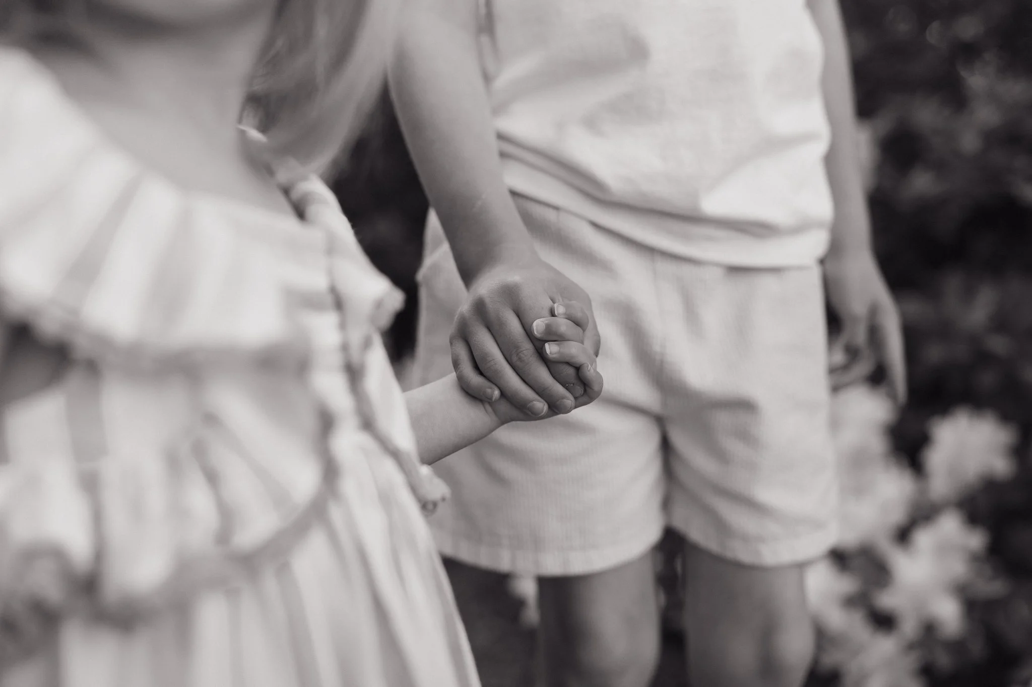 Children holding hands in a line, focusing on two kids' hands clasped together during a family photography shoot in Memphis, TN. 