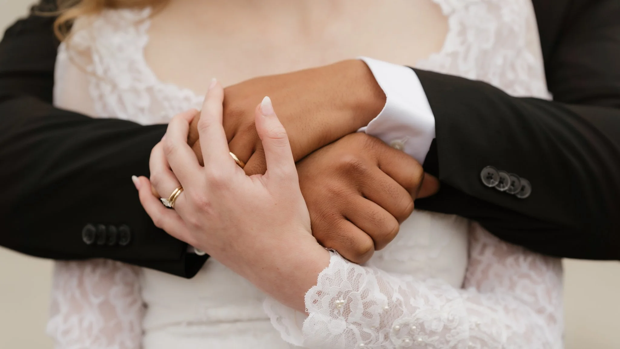 Couple holding hands during wedding ceremony, focus on their hands, bride wearing lace wedding dress and groom in black suit in Memphis, TN. 