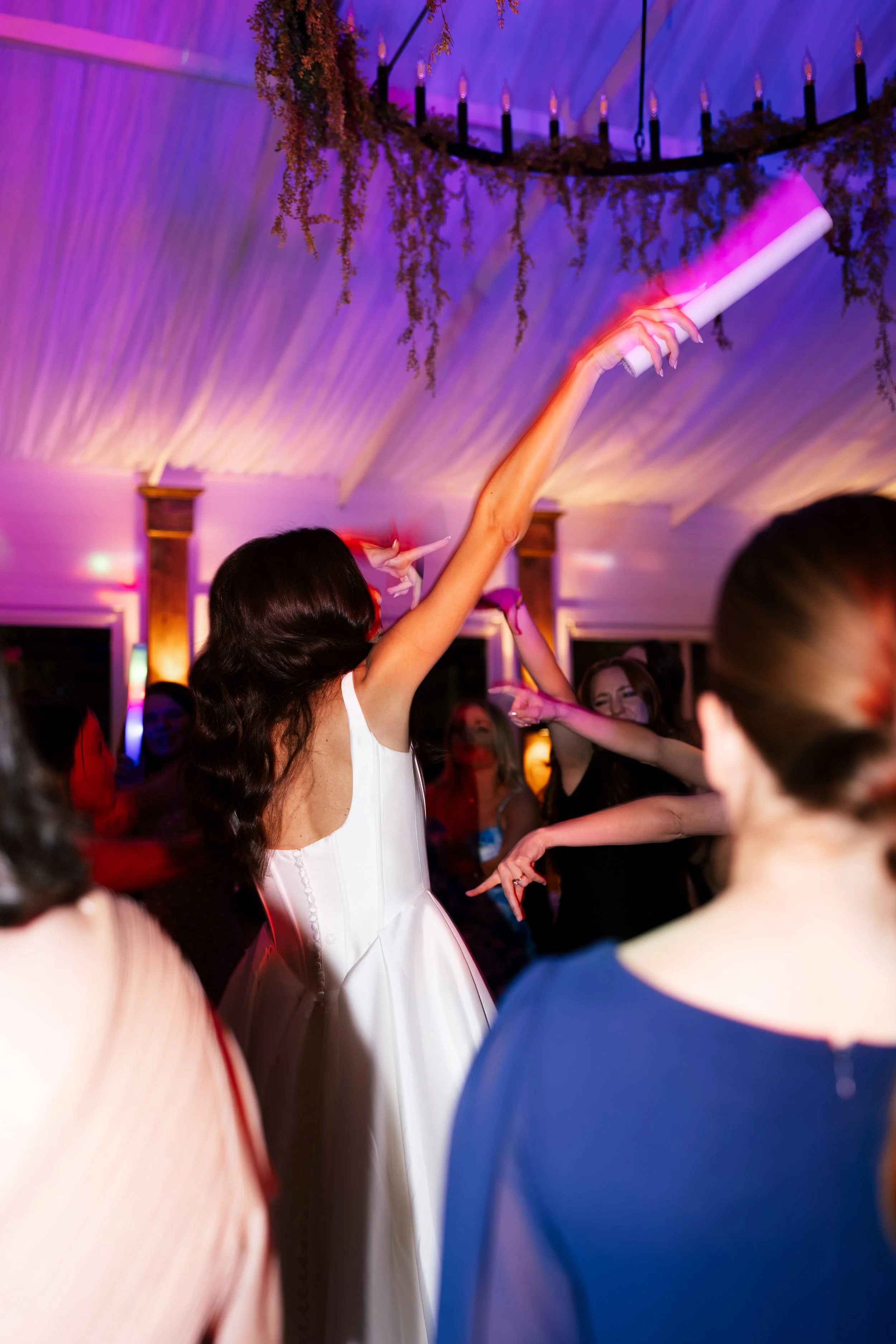 People dancing at a party or celebration, with colorful lighting and a chandelier hanging from the ceiling in Memphis, TN. 