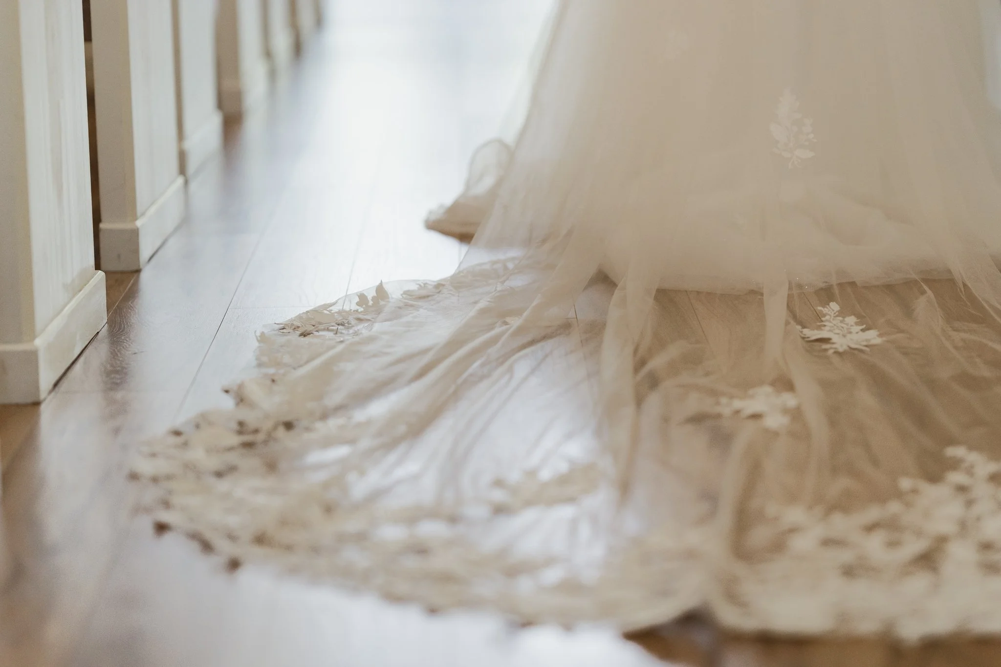 A close-up view of a wooden floor with a long strip of tattered, transparent plastic sheeting or fabric lying across it, near a white wooden railing in Memphis, TN. 