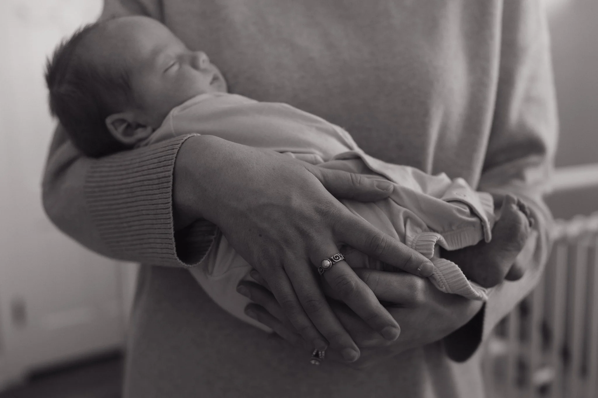 A person is holding a sleeping baby in their arms. The baby is lying on its back with eyes closed, and the person’s hands are gently supporting the baby's body in Memphis, TN. 