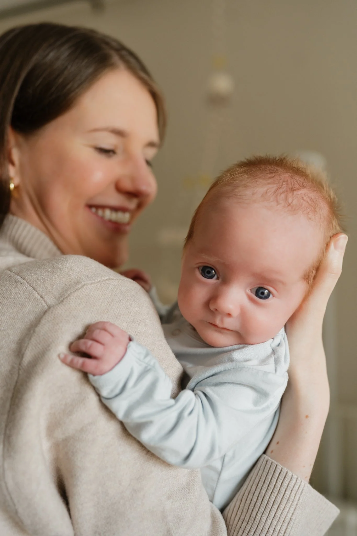 A woman smiling and holding a baby with red hair and blue eyes in Memphis, TN during an intimate newborn shoot.