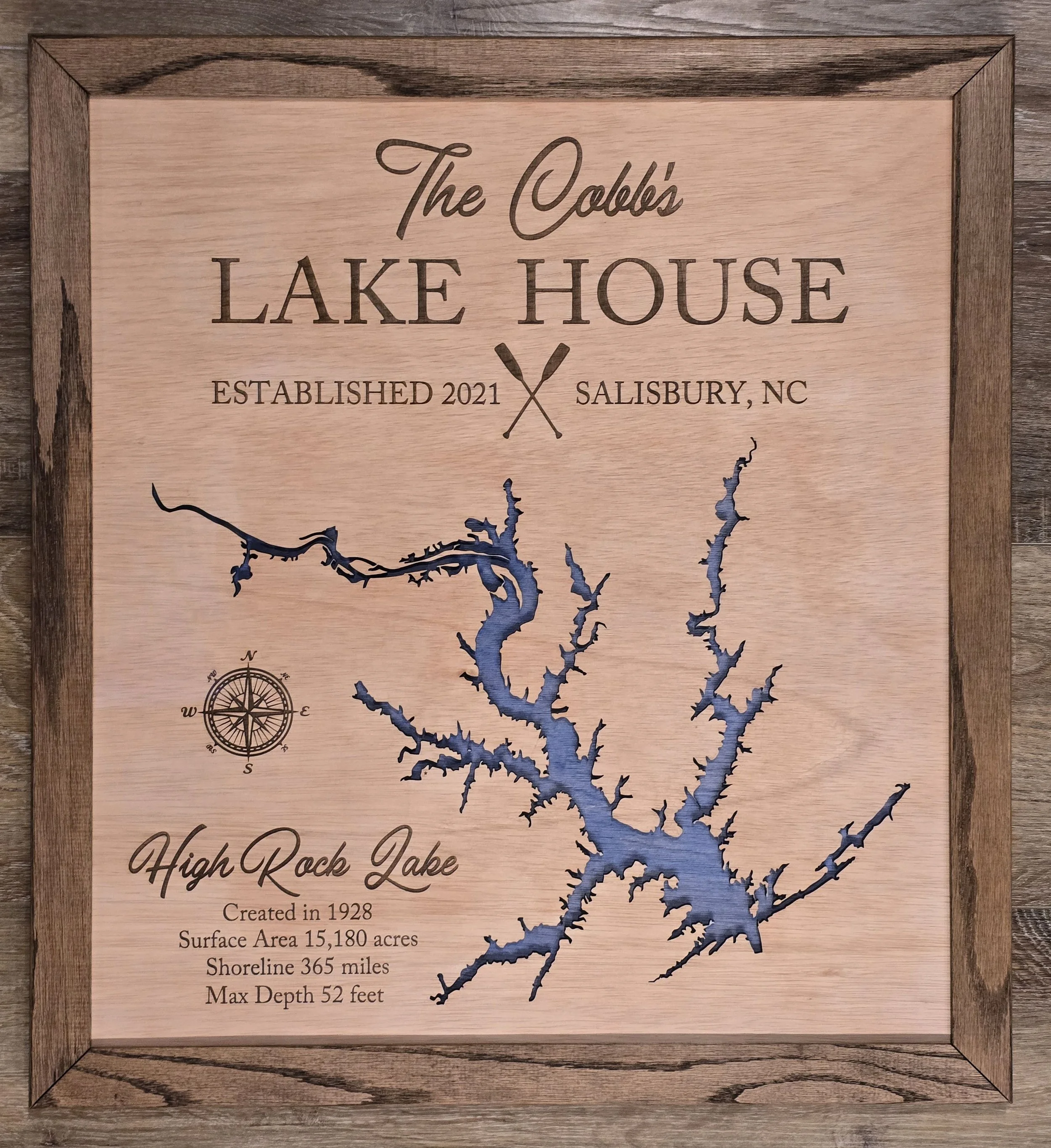 A wooden framed laser-cut and engraved map of High Rock Lake, North Carolina, showing its shape and details. Text indicates the lake was established in 1928, covers 15,180 acres, has a shoreline of 365 miles, and a maximum depth of 52 feet.