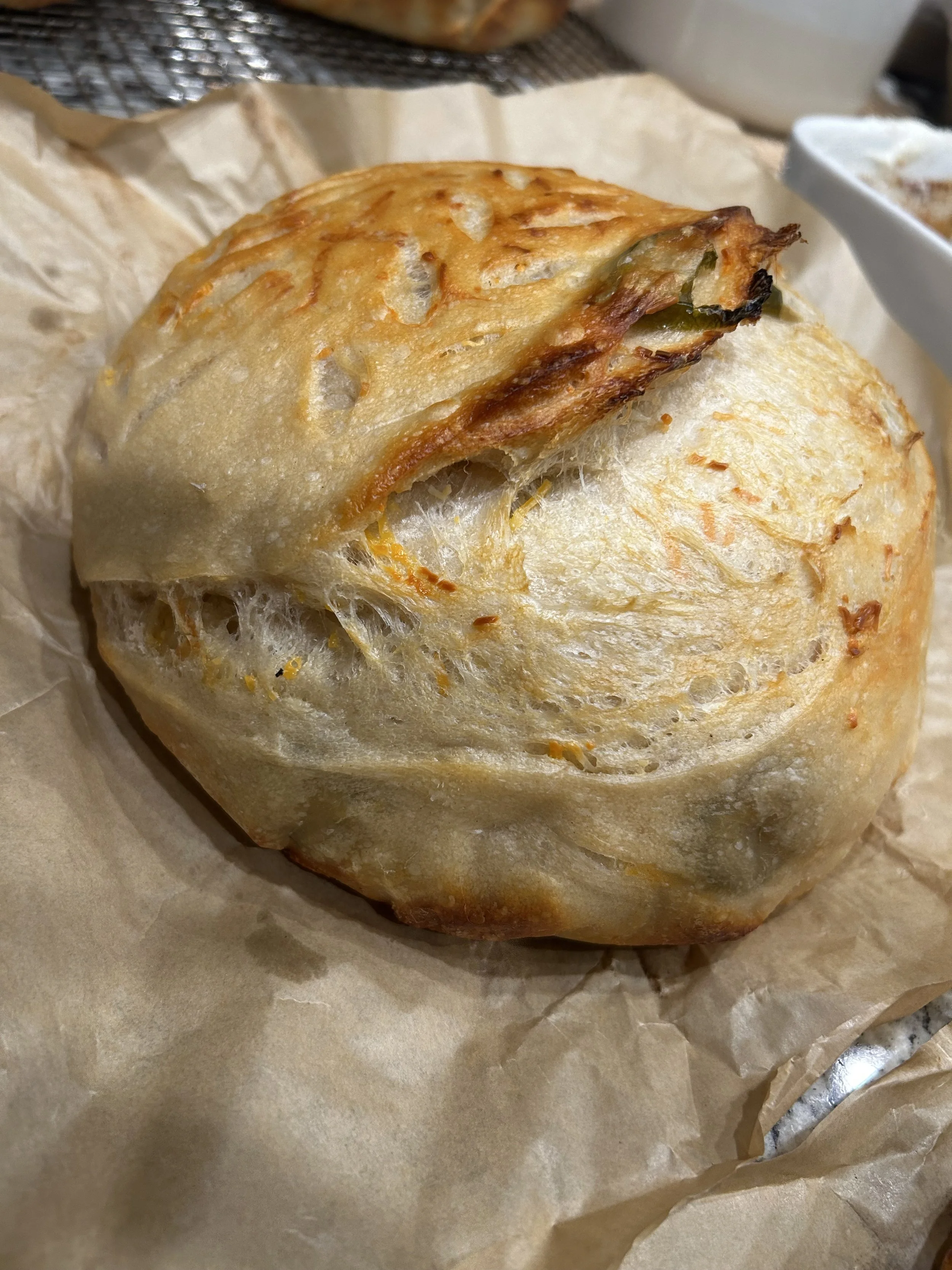 Baked bread roll with a crispy crust resting on brown parchment paper.