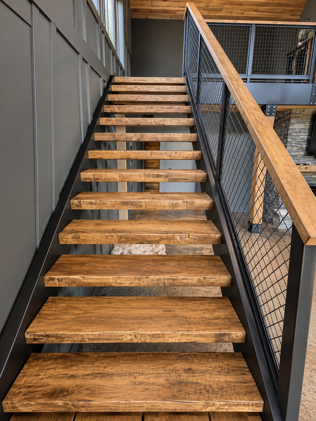 Wooden staircase with black metal framing and railings inside a house.