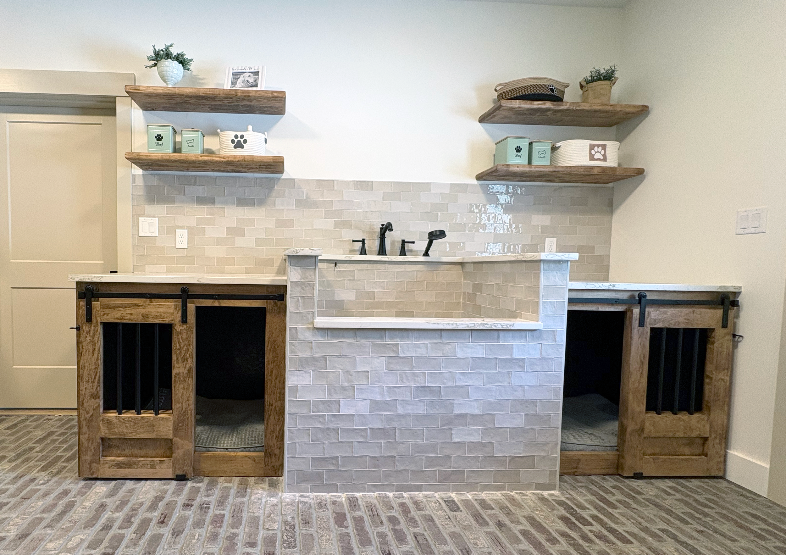 A kitchen island with a brick base, black faucet, and wooden frame, surrounded by open wooden shelves against a white wall with beige tile backsplash.