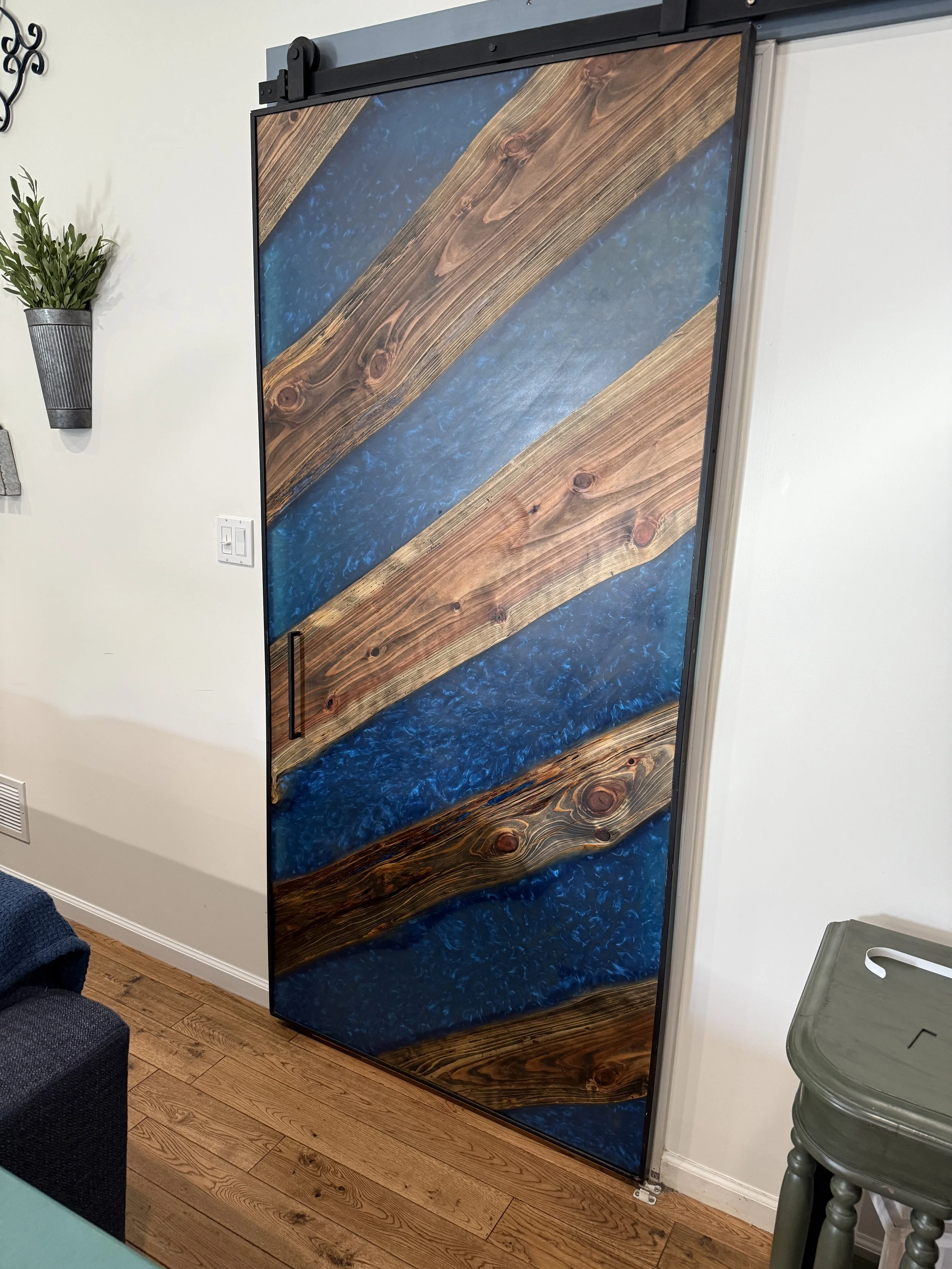 Sliding barn door featuring a wood grain pattern with blue resin river inlays.