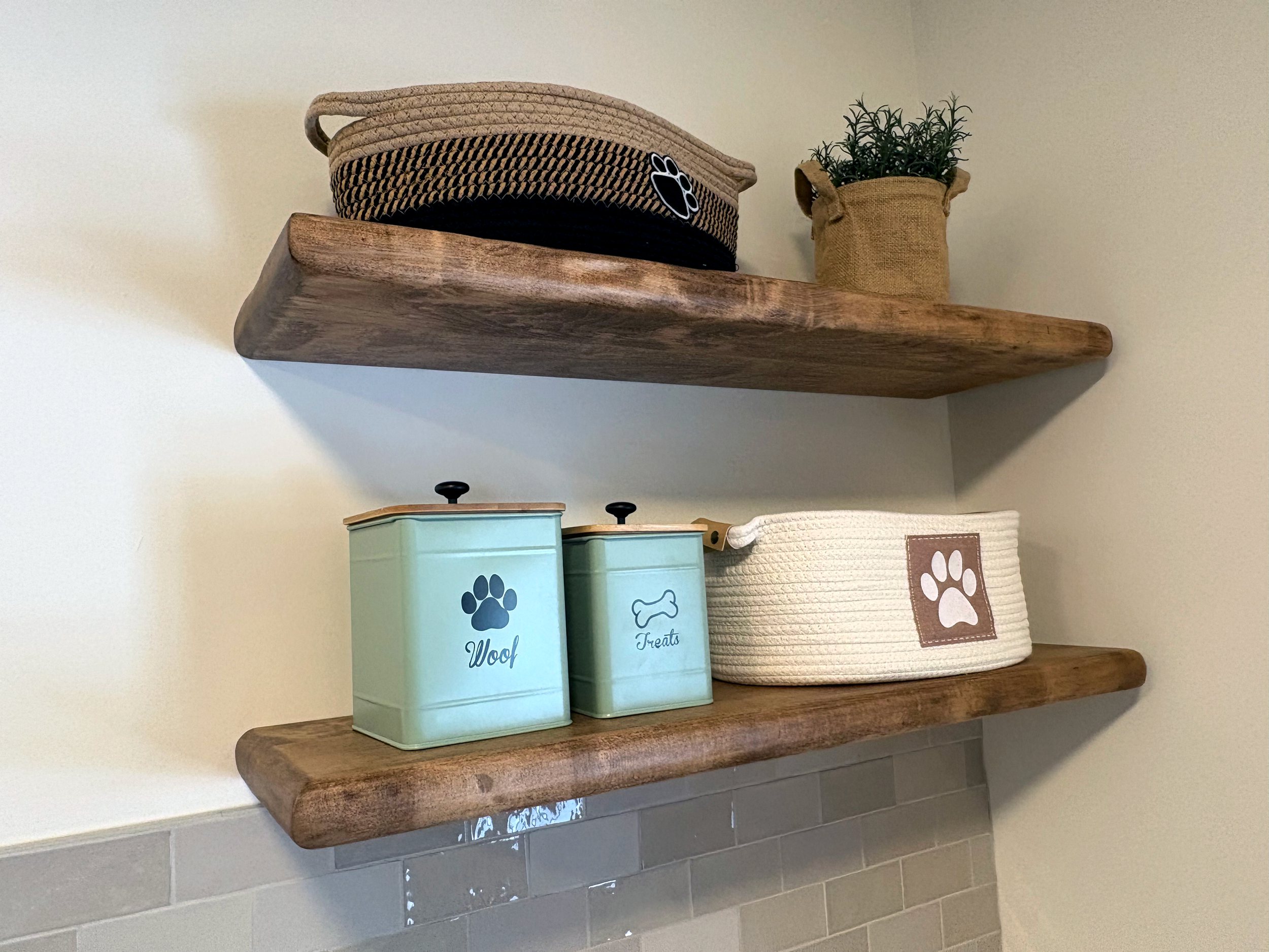 Wooden shelves holding pet-themed storage containers and decorative items, including a woven basket with a paw print, a pot with a plant, and boxes labeled "Woof" and "Treats."