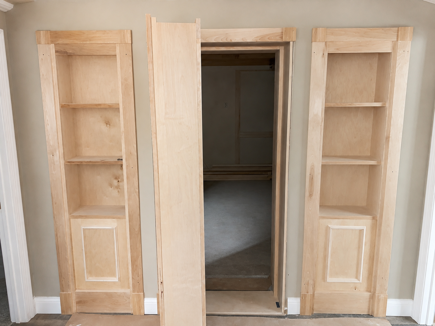 unfinished built-in wooden shelves with open storage on either side of a doorway leading to a walk-in closet.