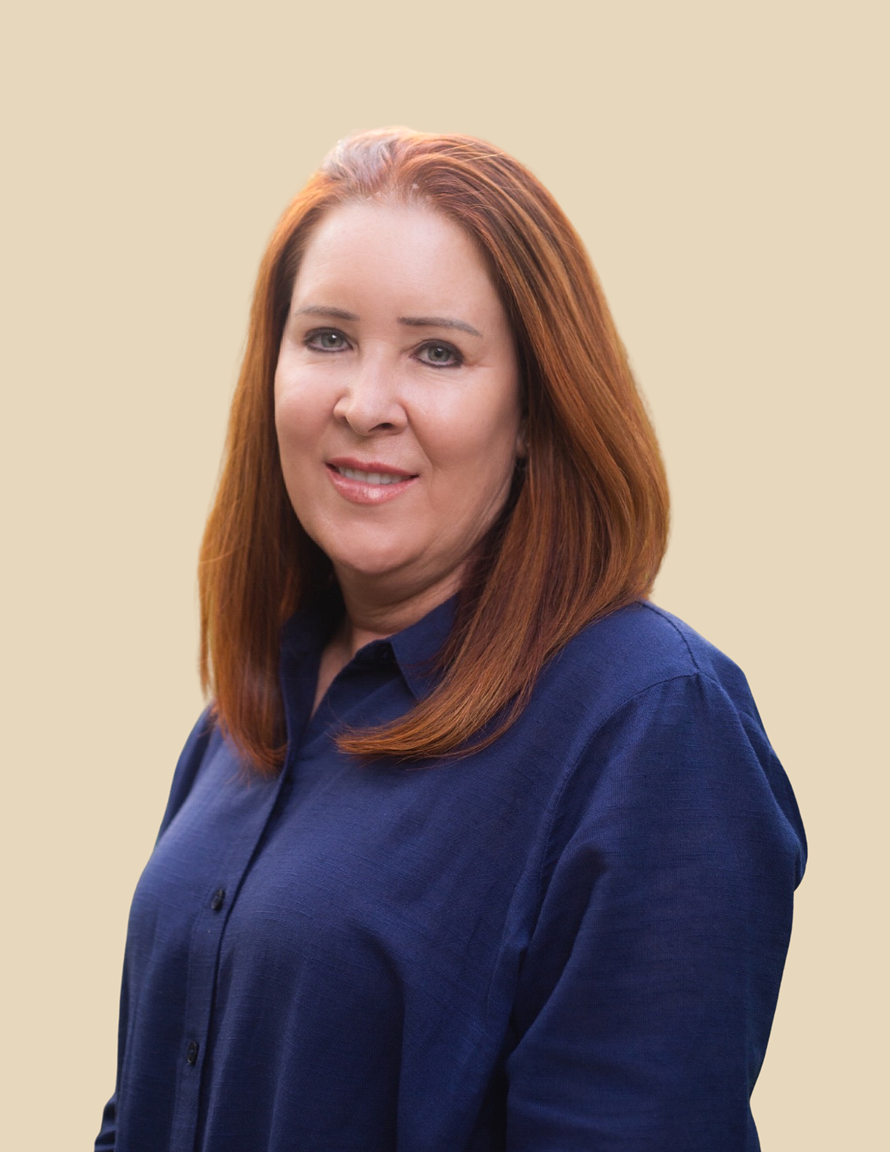 A woman with long red hair, smiling warmly outdoors against a green background. Dori Arden, Administrative Coordinator at ThirdSpace Psychotherapy, New York City.