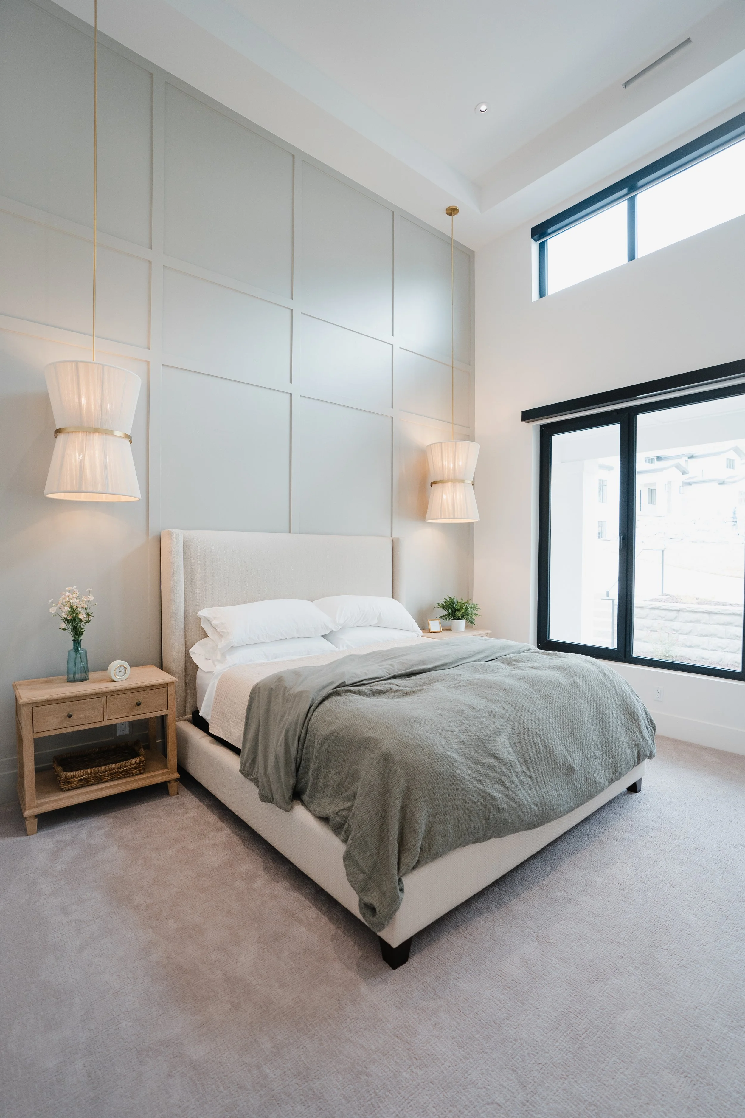 Bright master bedroom with large windows and neutral decor