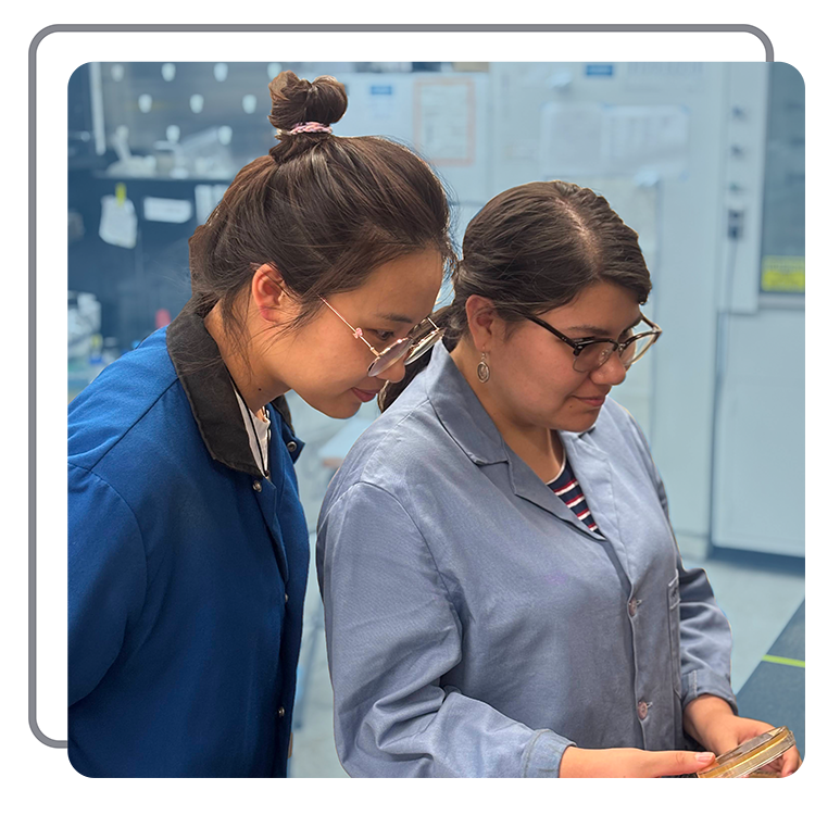 Two women in lab coats examining a smartphone in a laboratory setting.