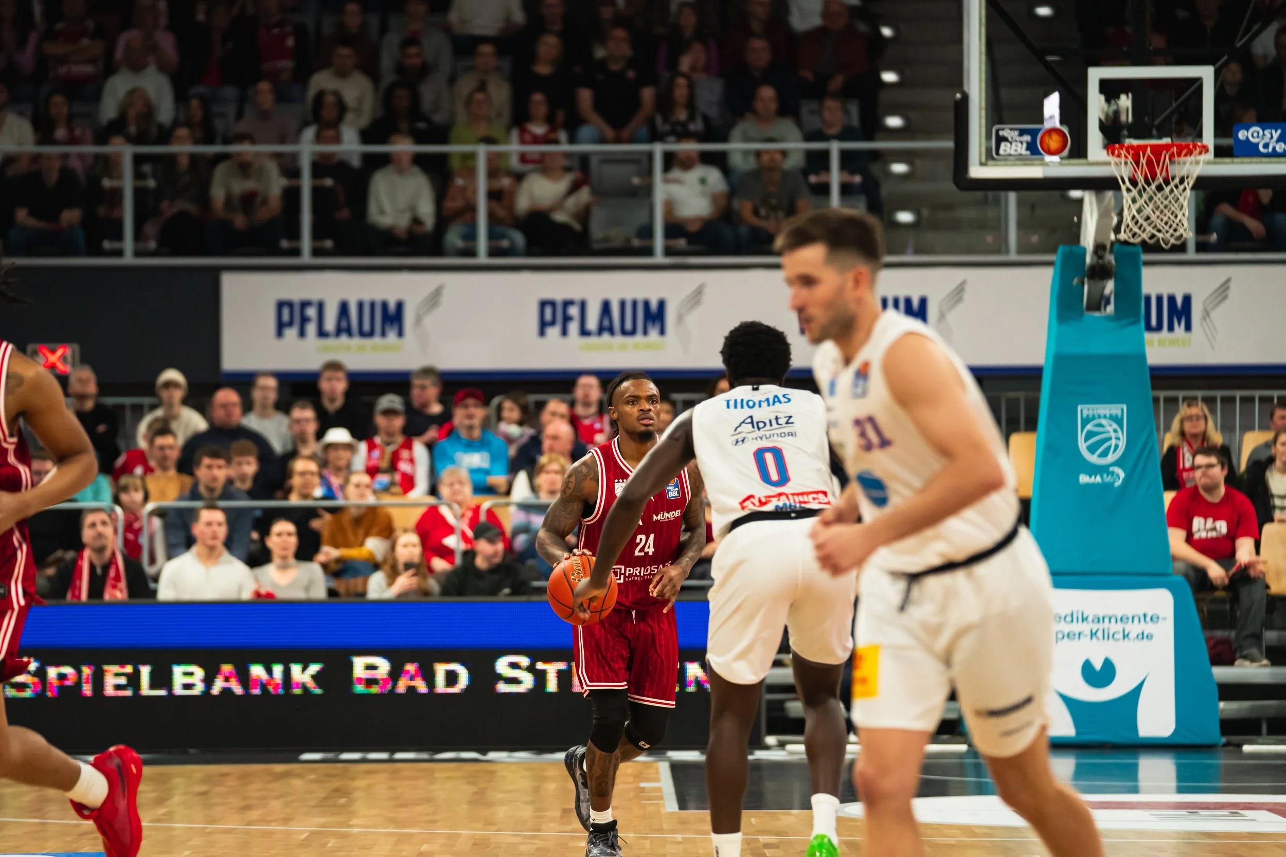 Basketballspieler im Spiel auf einem Basketballfeld, Zuschauer im Hintergrund.