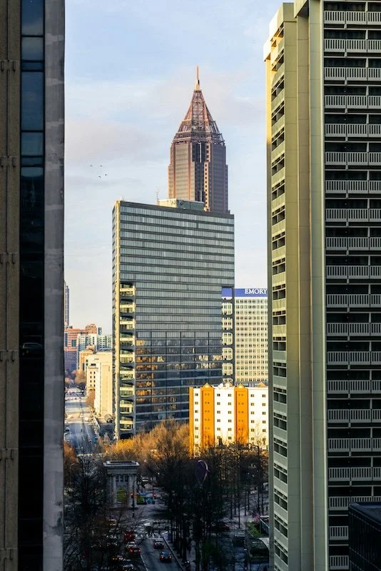 Cityscape with skyscrapers, including the iconic Empire State Building in New York City, and a view of a street with trees and buildings.