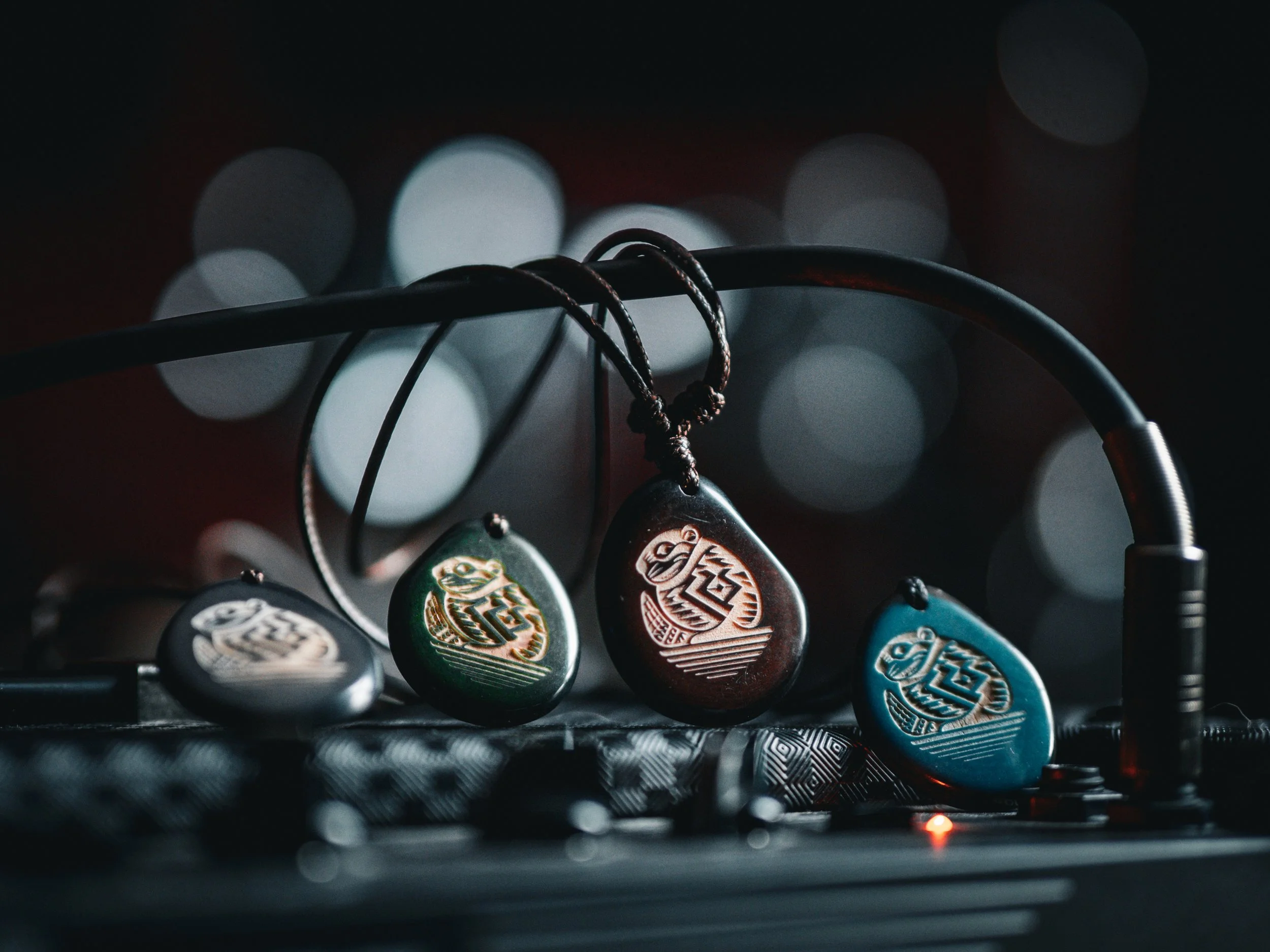Vier Gitarren-Plektren mit Turtle-Designs auf einem Mixer, dunkler Hintergrund mit Lichter-Bokeh.