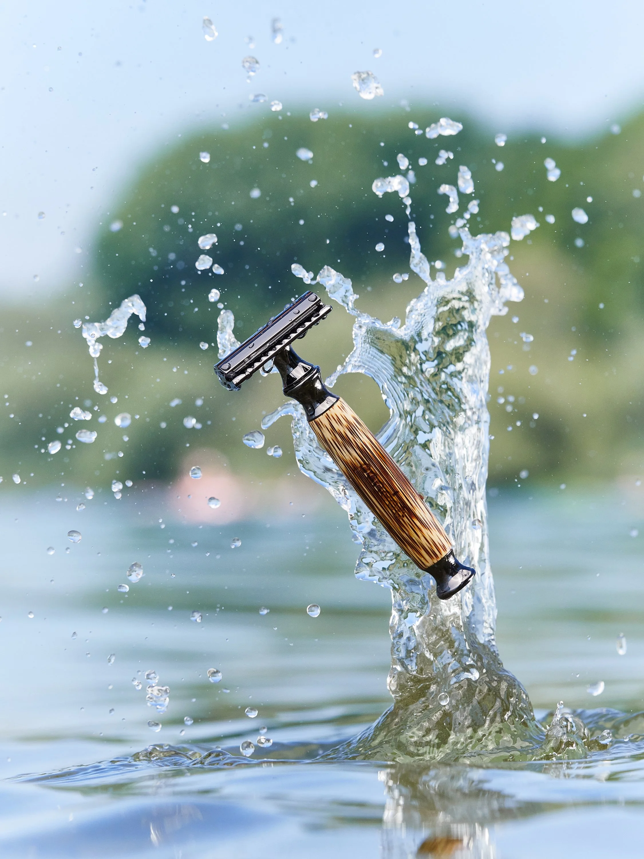 Rasierer, der in das Wasser fällt und Spritzwasser erzeugt