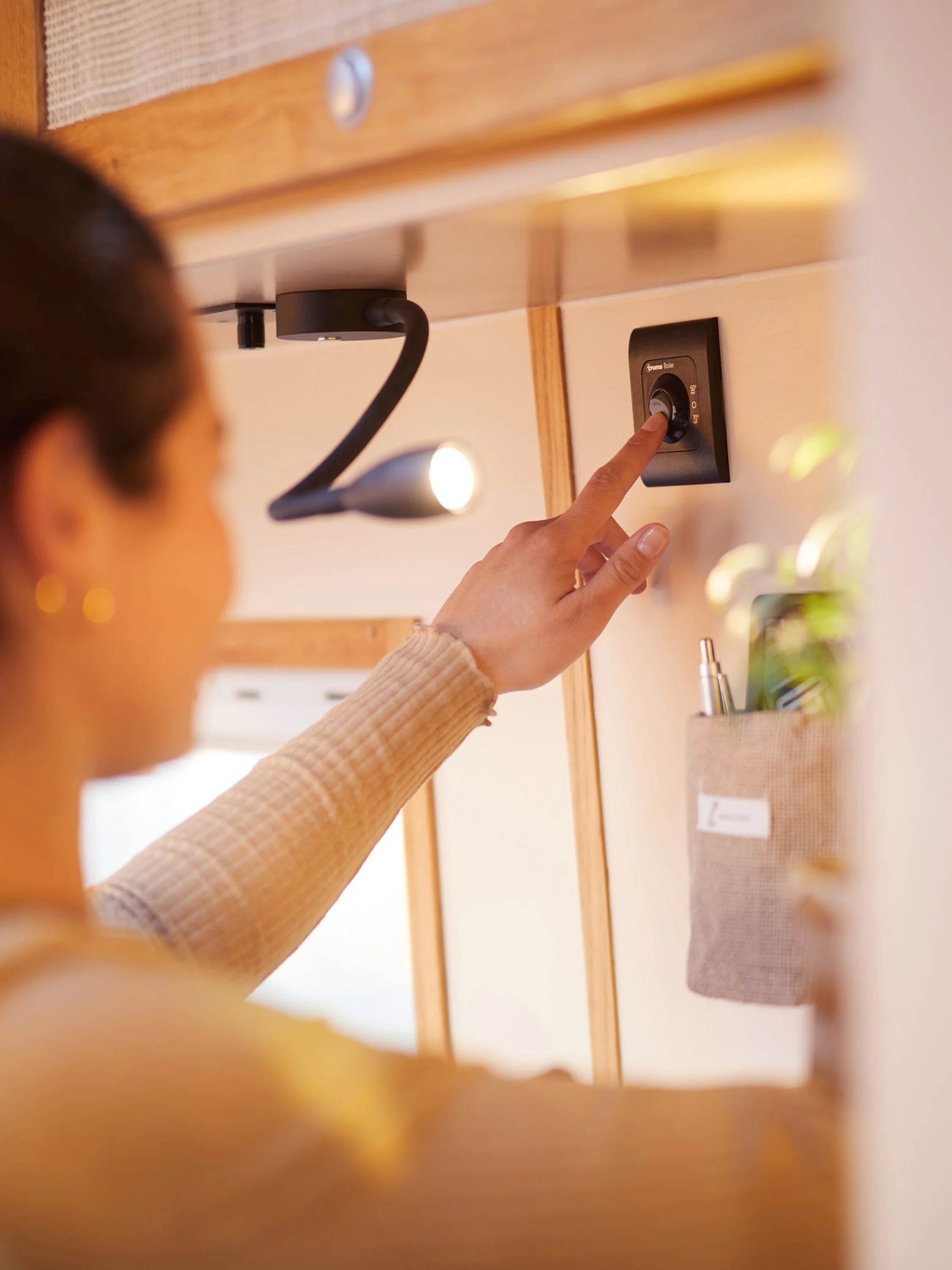 Eine Frau betätigt einen schwarzen Dimmer-Schalter an der Wand meines Hauses, um die Beleuchtung zu steuern.