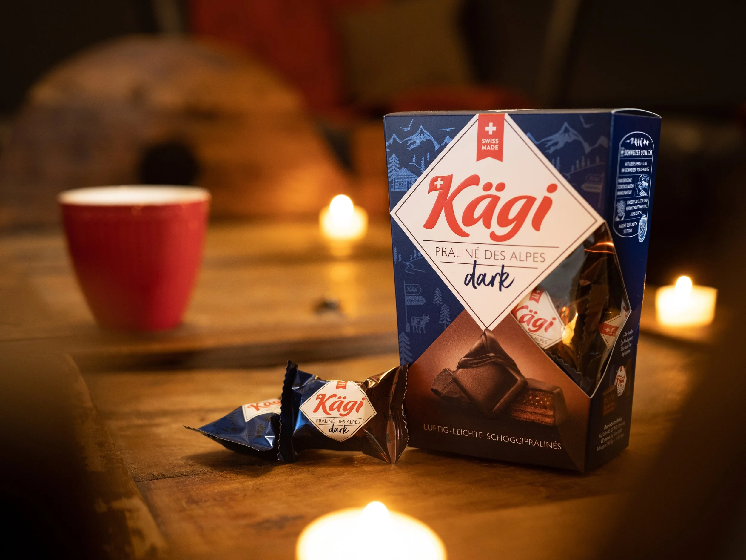 Schweizer Schokolade Käger auf einem Holztisch mit Kerzen im Hintergrund.