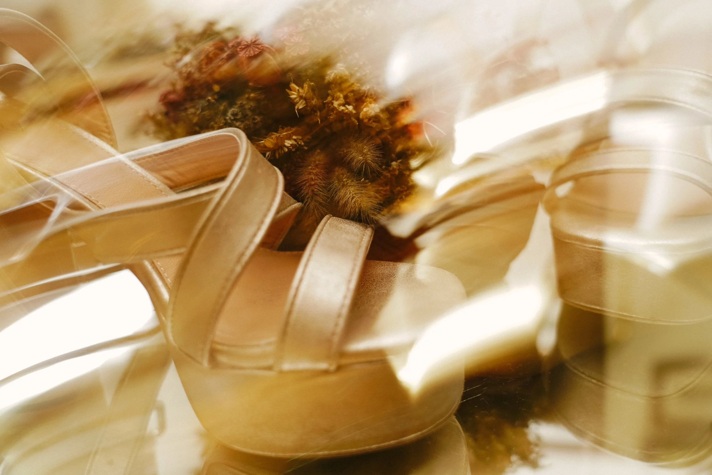 Zapatos de tacón de color dorado con una abeja descansando en flores secas en su interior