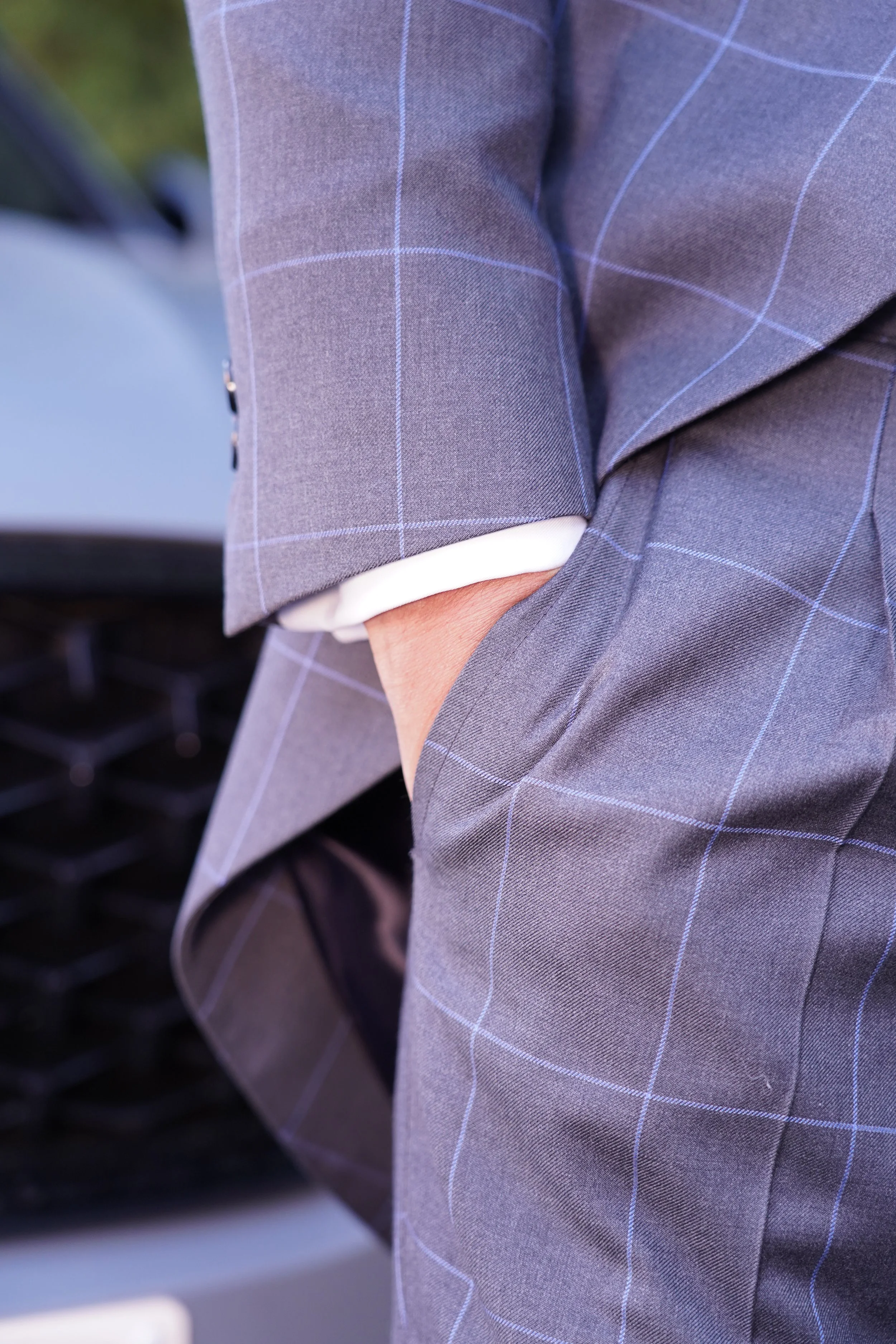 Persona con traje gris con cuadros azules, con la mano en el bolsillo.