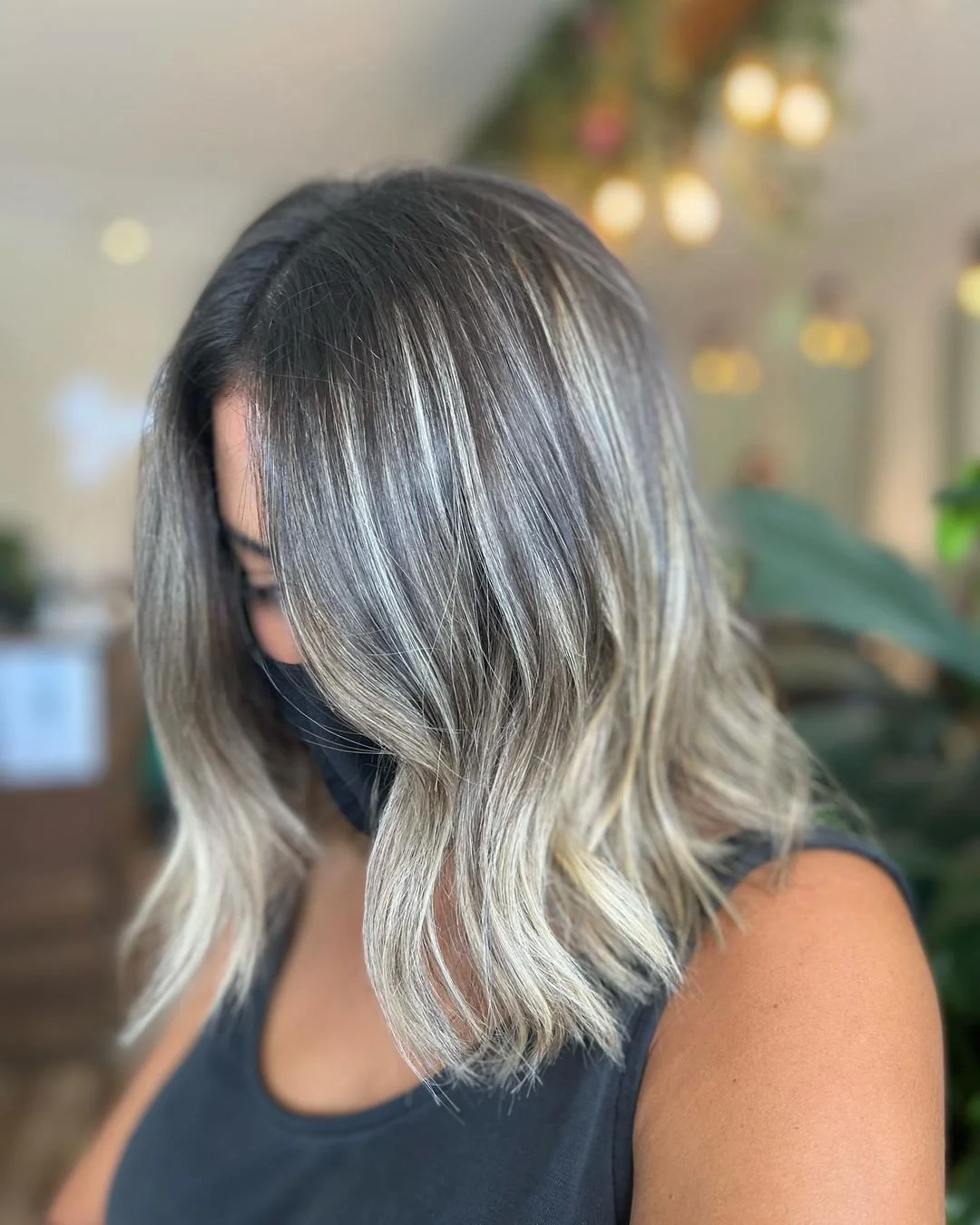 A woman with shoulder-length hair that is dark at the roots and transitions to blonde in loose waves.