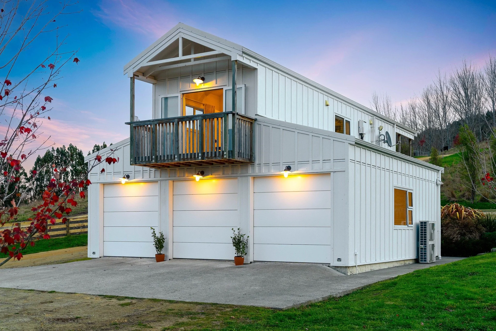Barn style white house at dusk with blue/pink sky in background.