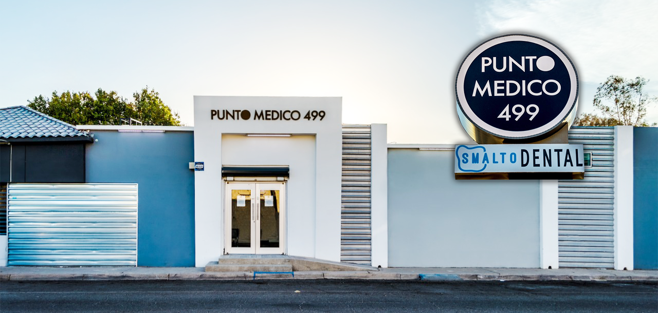 Clínica médica y dental con señalización que dice 'Punto Médico 499' y 'Smalt Dental' en un edificio de color azul y blanco.