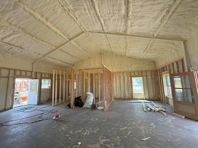 Interior of a house under construction with exposed wooden framing and insulation on the ceiling.