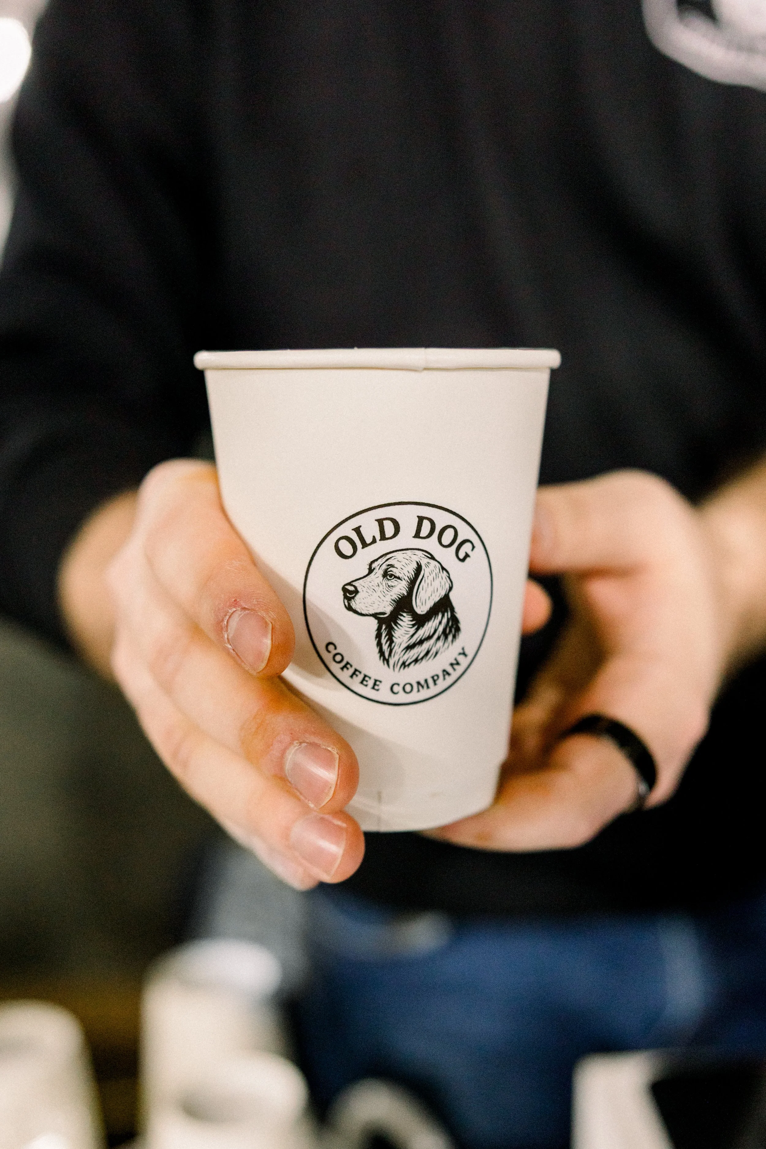 Old Dog Coffee Cart Catering serving a cup at a catering event with an Old Dog Coffee Company logo on a hot cup with a latte handing from a barista to an event guest. Serving from a mobile coffee bar during catering service in Utica, New York.