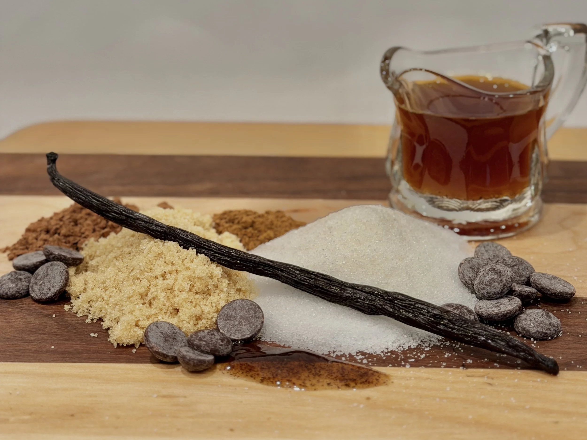 Raw ingredients used to make homemade latte syrups for mobile espresso bar catering in Utica, New York. Sugar, brown sugar, vanilla bean, vanilla bean paste, homemade vanilla extract, cocoa, cinnamon, chocolate.