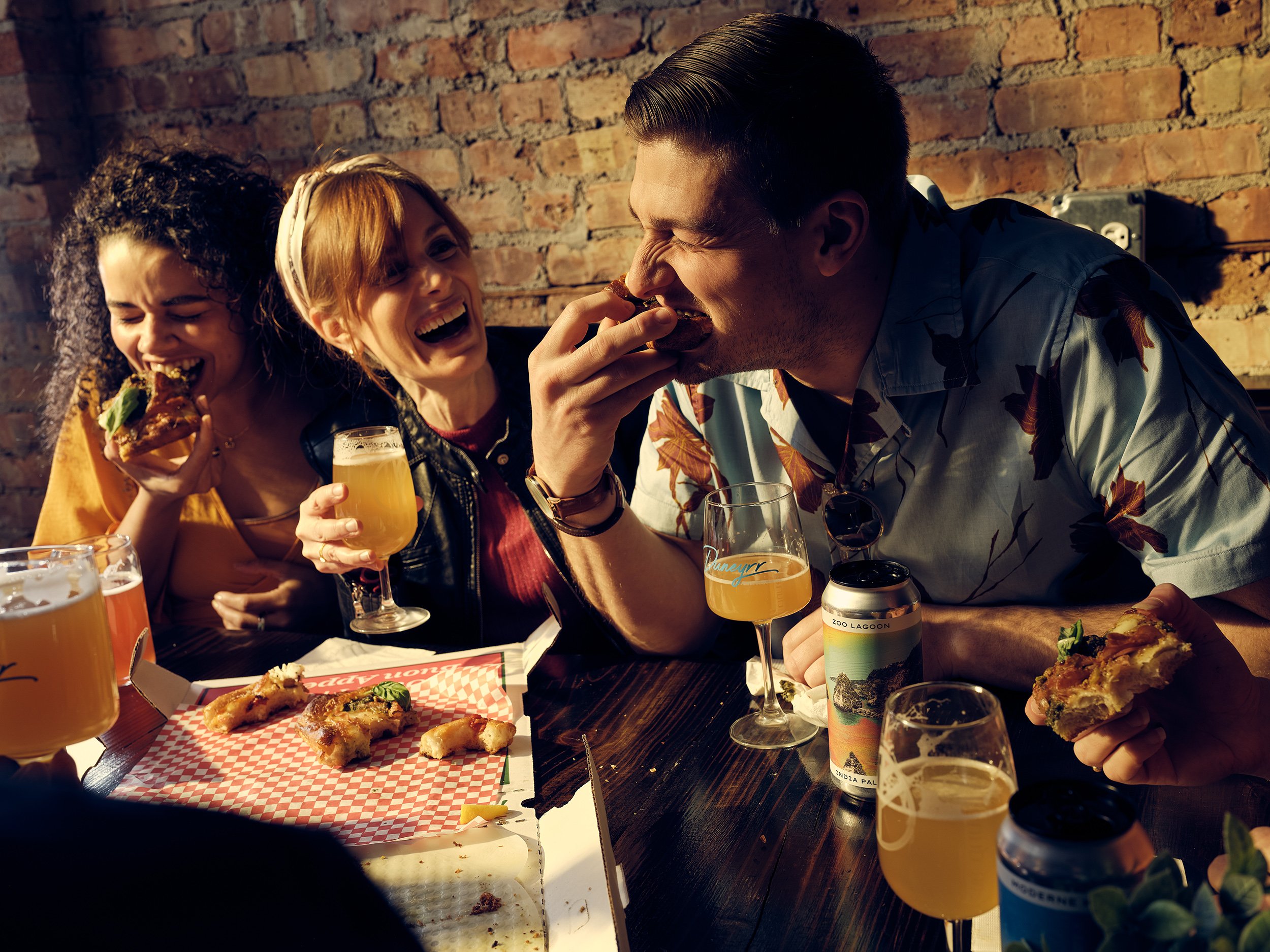 A group of friends sharing pizza and drinks at a cozy birthday celebration, laughing and enjoying together.