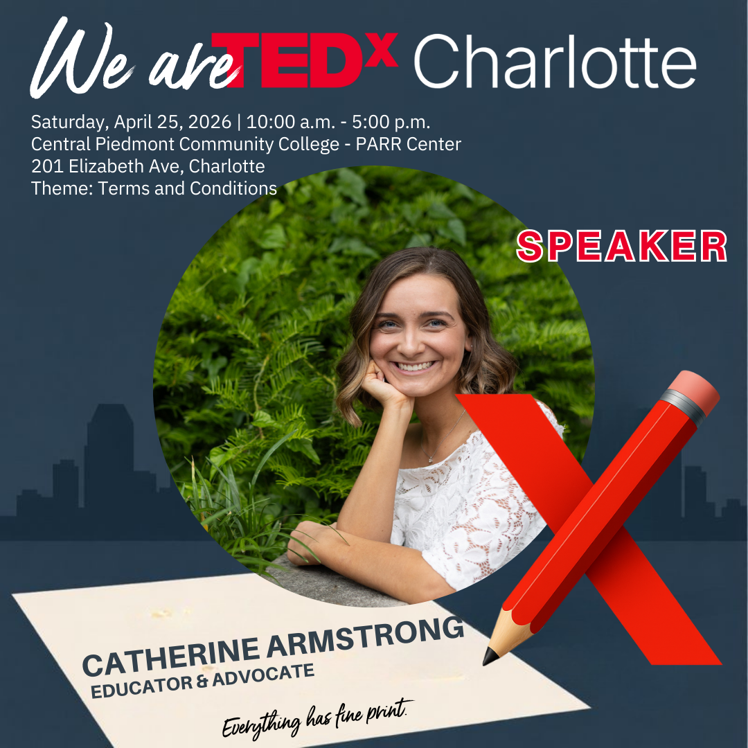 Black and white photo of a woman with dark hair, tattoos on her arm, wearing a t-shirt and a necklace, smiling slightly and resting her head on her hand.