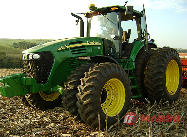 Trator verde da John Deere com rodas grandes em campo agrícola.