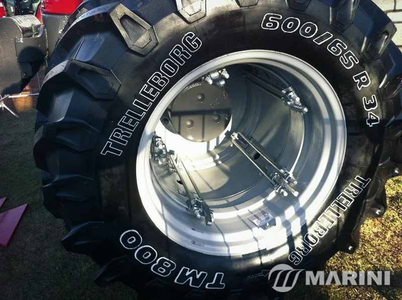 Pneu de trator agrícola com rodas reutilizáveis, exibindo marca Trelleborg, modelo TM 800, e detalhes internos do aro da roda.