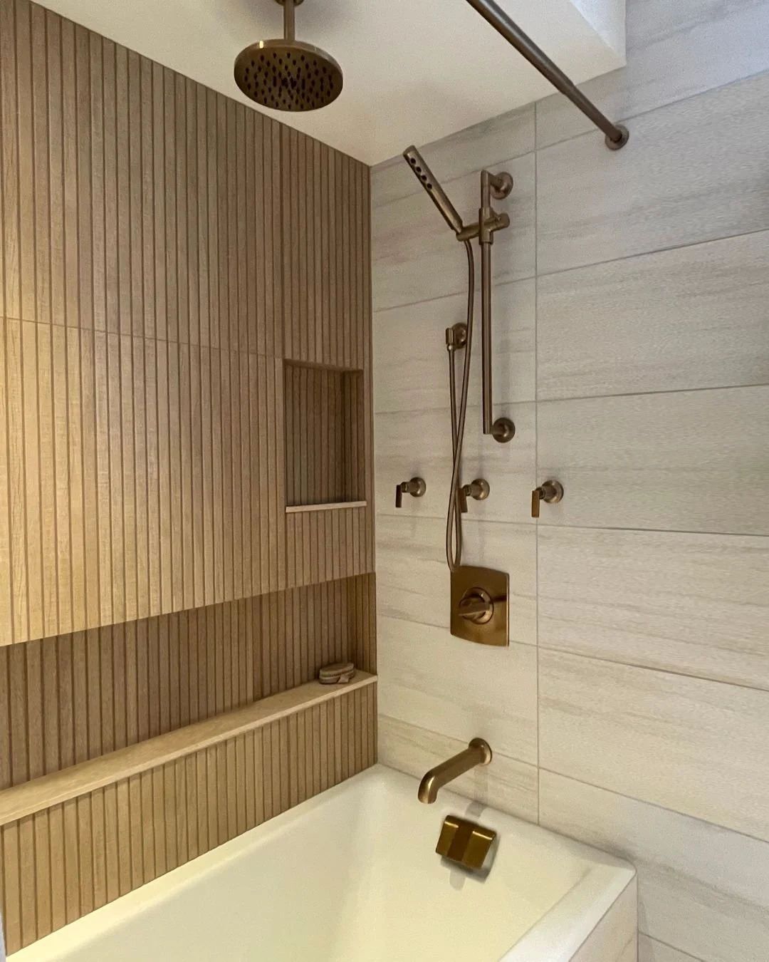 Who says you can't transform your small bathroom space into your own spa-like oasis? This newly designed bathroom features warm wood tone tiles, built-in shelving, and elegant brushed bronze fixtures, creating a serene and luxurious retreat. 😌

Inte
